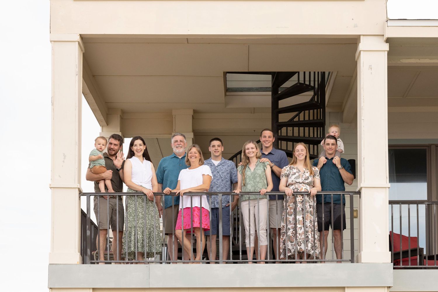 Group of people standing on a white balcony with columns during a sunny day.