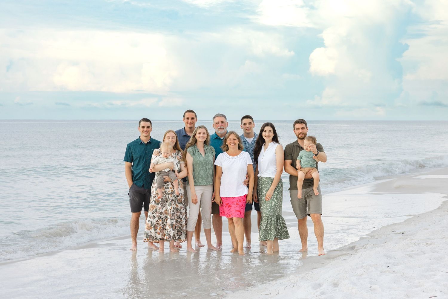 Group of people walking together on a scenic beach with waves and blue sky in the background.