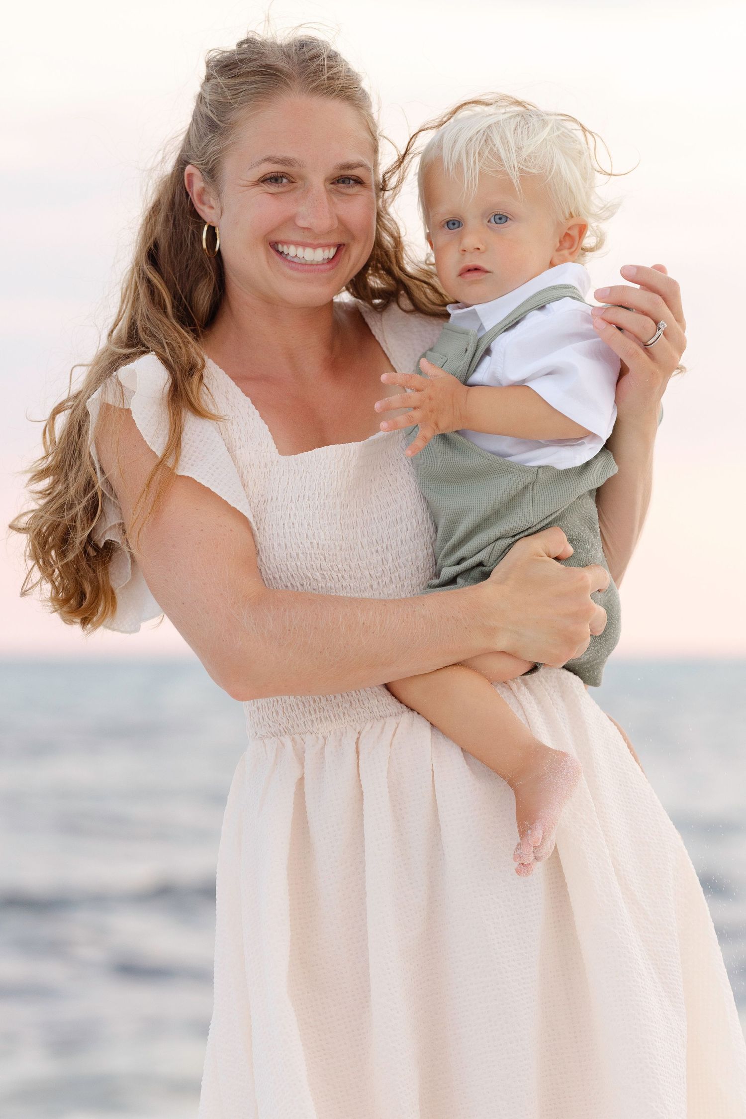 Sweet candid sunset beach moments with coordinating outfits in soft pink lighting.