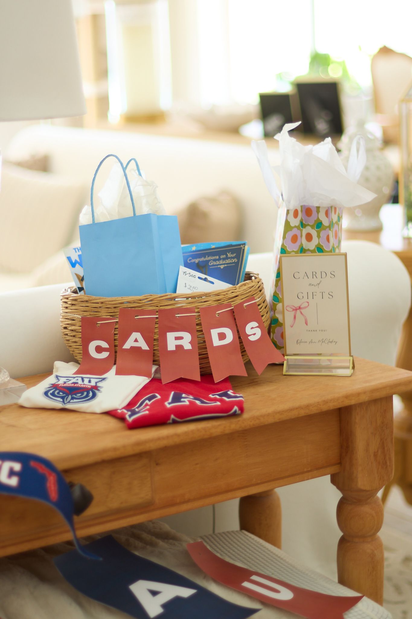A wooden table displays gift cards, merchandise, and a woven basket with party supplies.