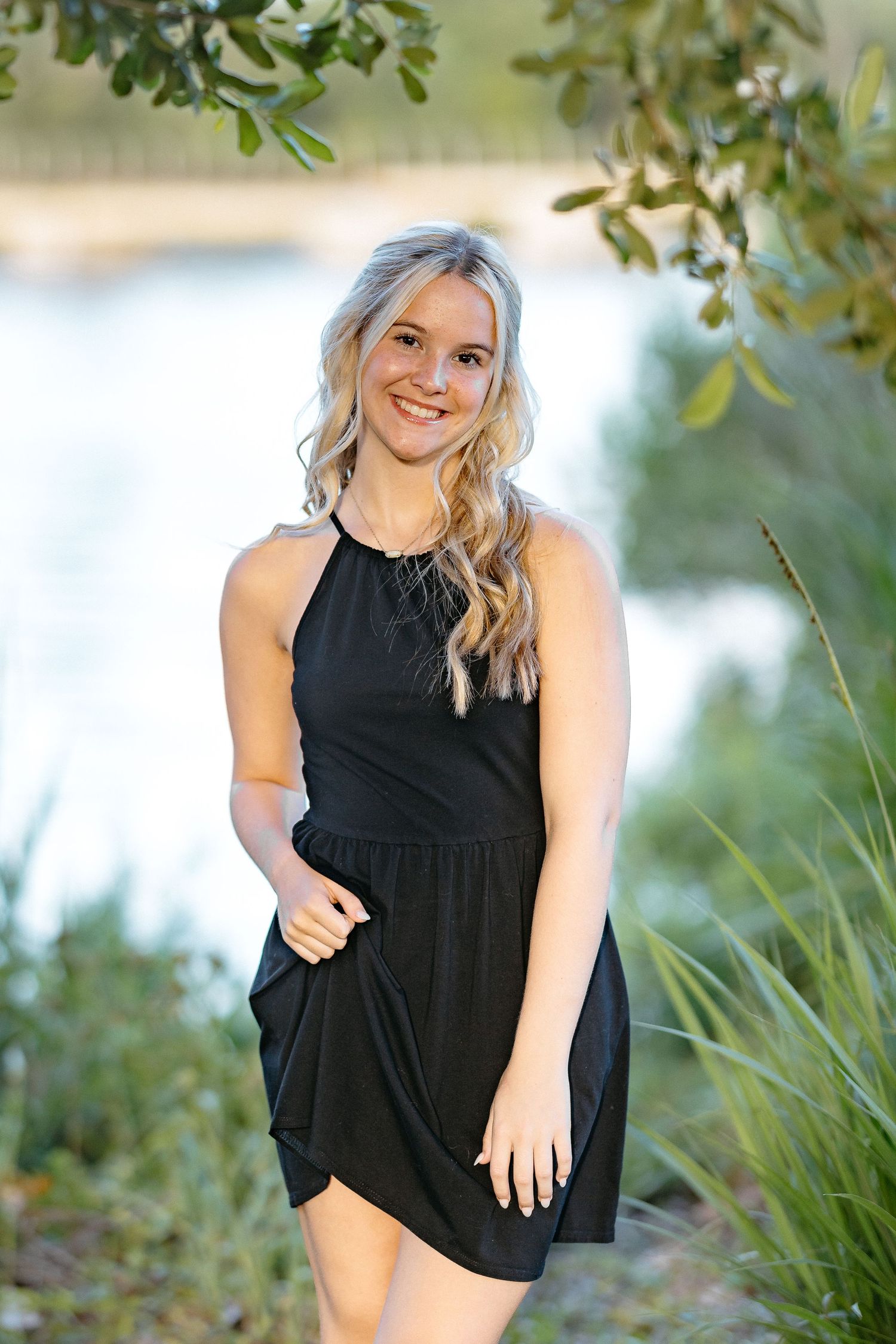 Lifestyle portrait session among trees and greenery near a waterfront location.