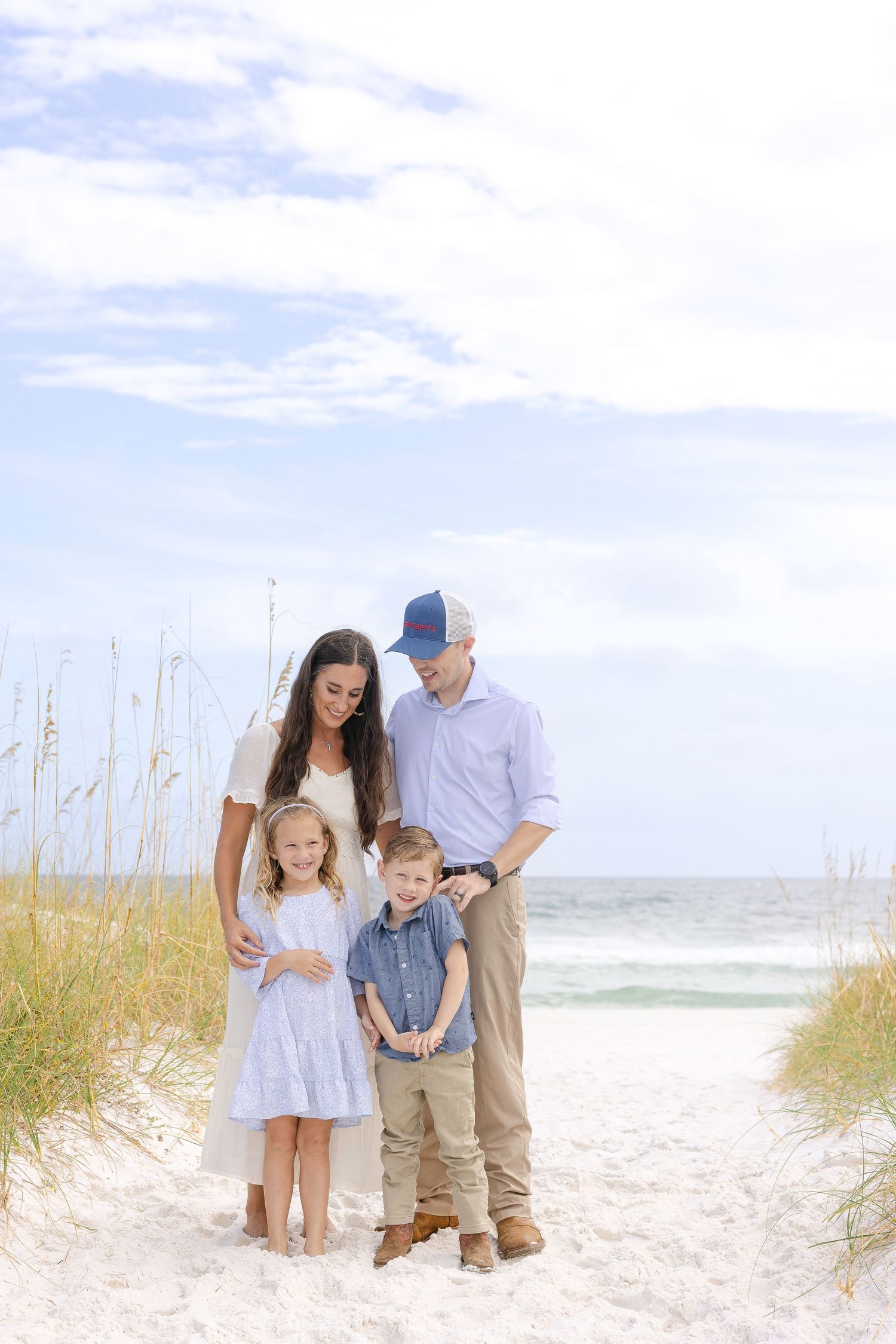 Small family group walking along pristine white sand beach with ocean waves in background.