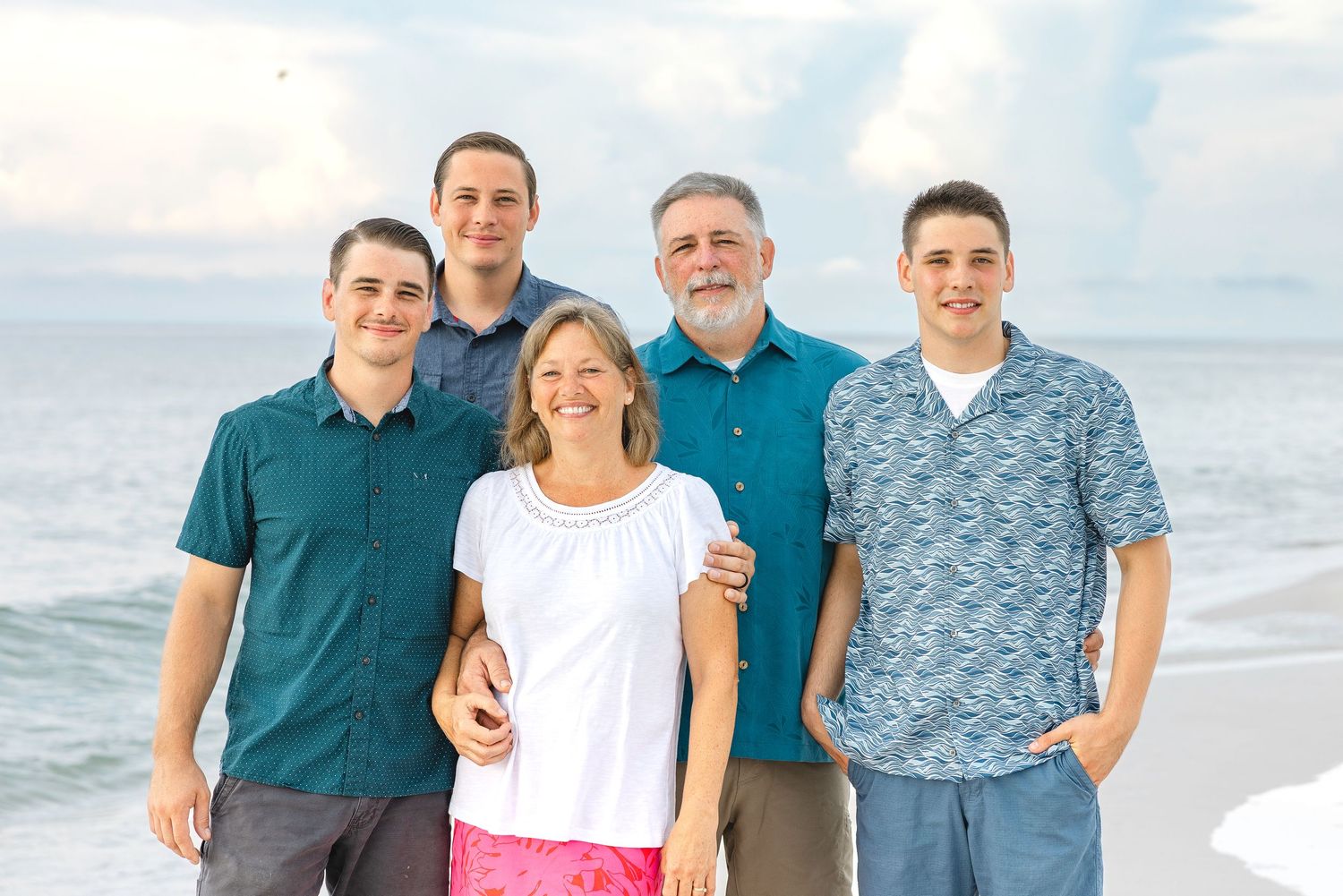A group enjoying a sunny day together at the beach with ocean waves and blue sky in background.