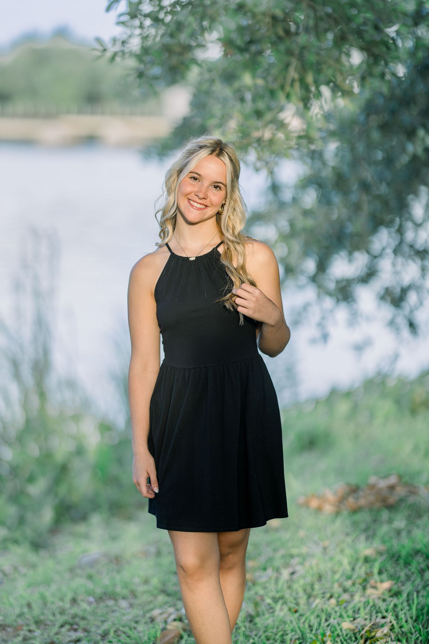 Casual outdoor photography featuring a black dress in a natural waterfront setting.