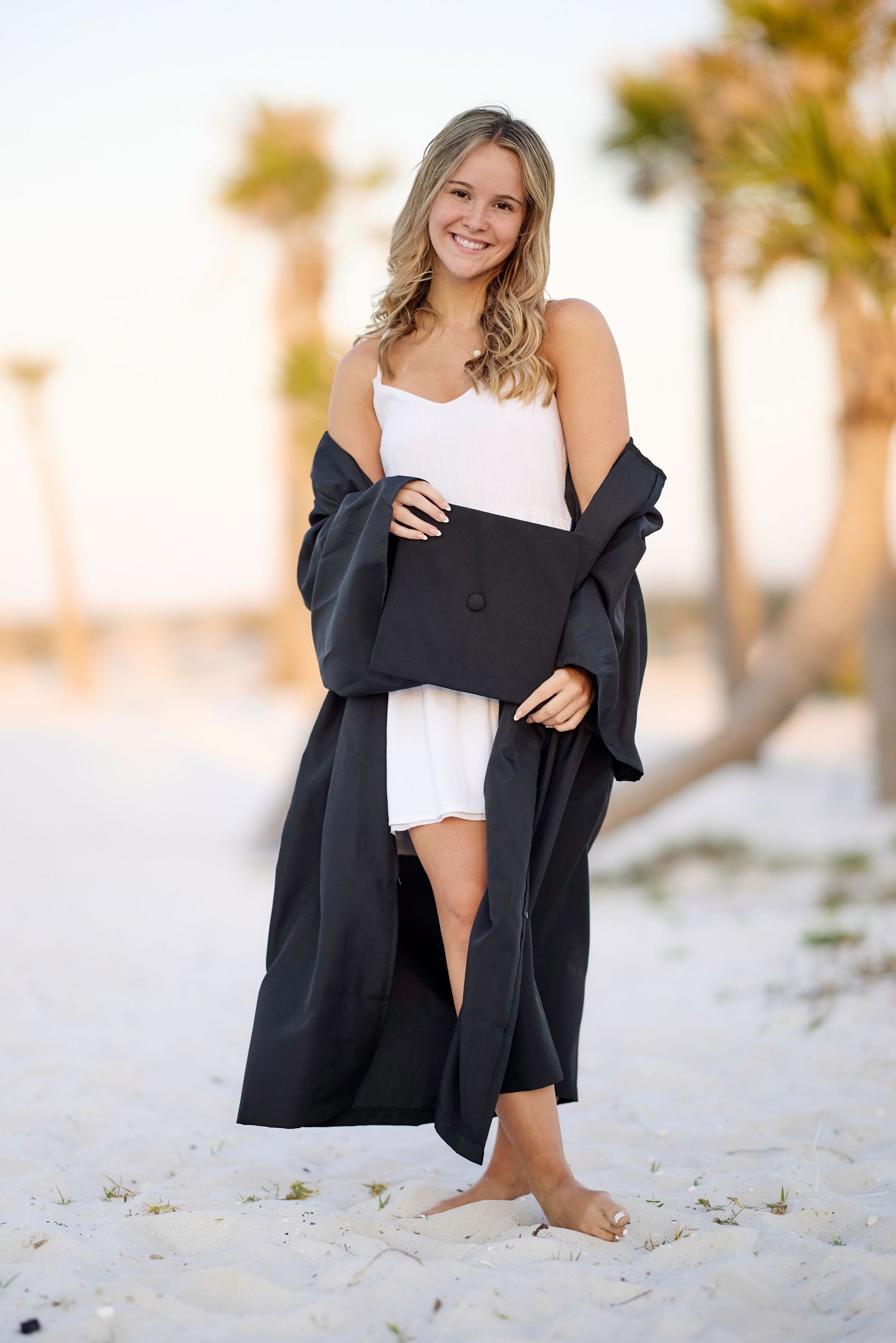 Professional beach portrait photography session featuring casual white top and black cardigan on sandy white beach.