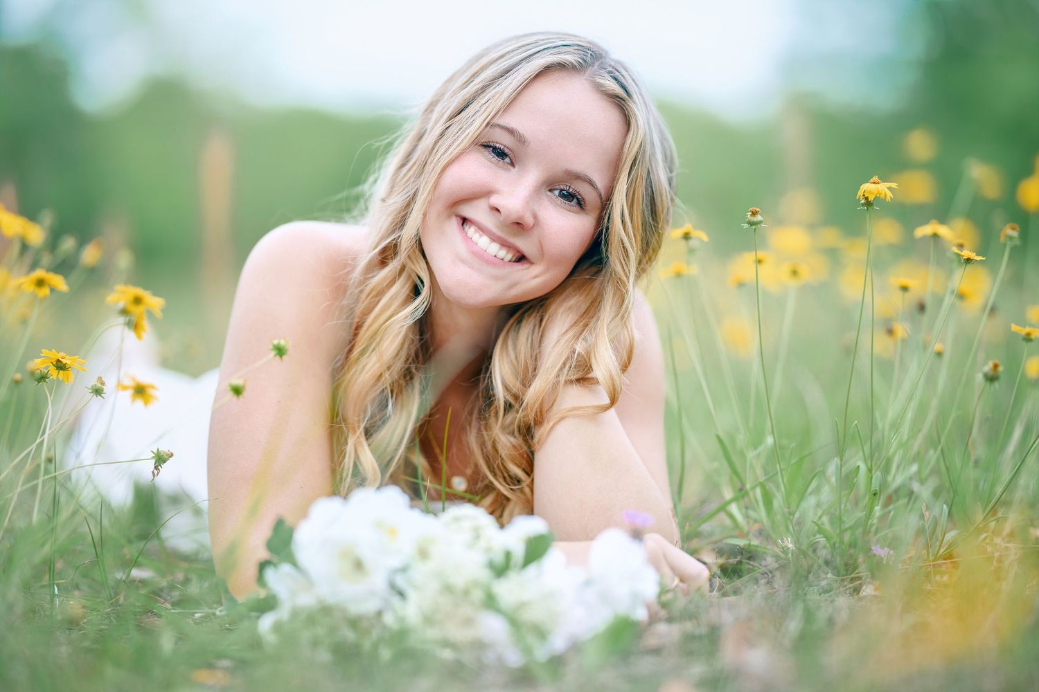 Dreamy outdoor portrait among yellow wildflowers and white blooms.