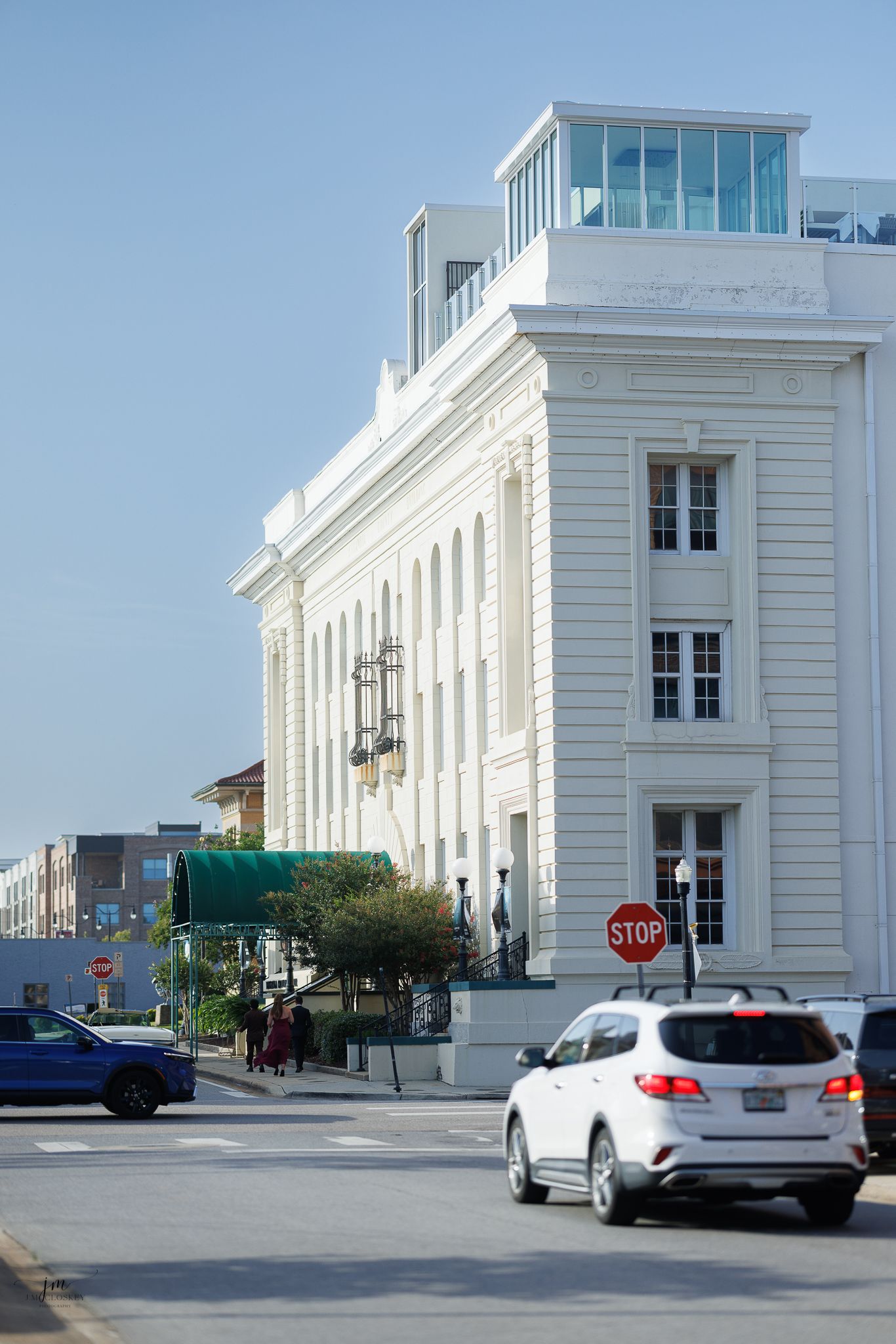A series of exterior views showing different angles of a modern white commercial building with glass windows and parked cars.