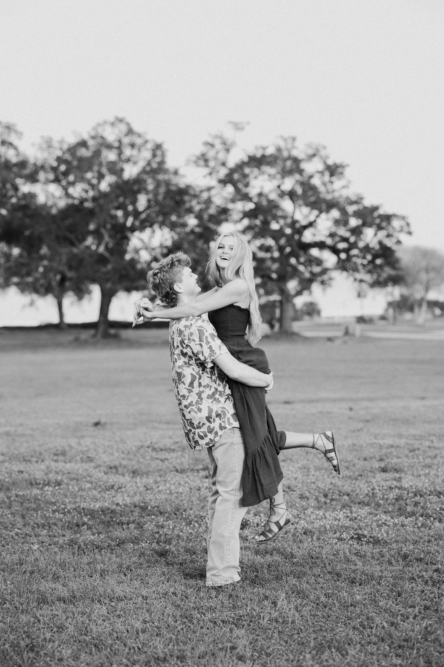 A romantic black and white photo sequence shows a couple embracing and spinning together in a grassy field with trees.