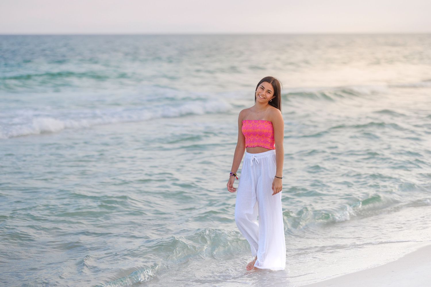 A series of people enjoying the beach at sunset with relaxed poses and white outfits against crashing waves.