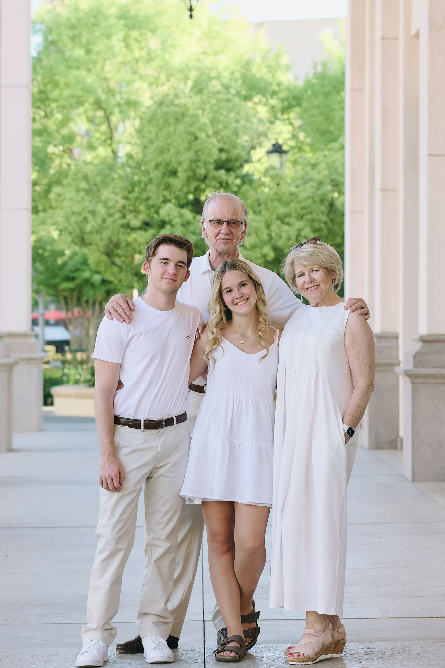 Four lighthearted candid photos taken under a covered walkway with white columns and green trees in background.