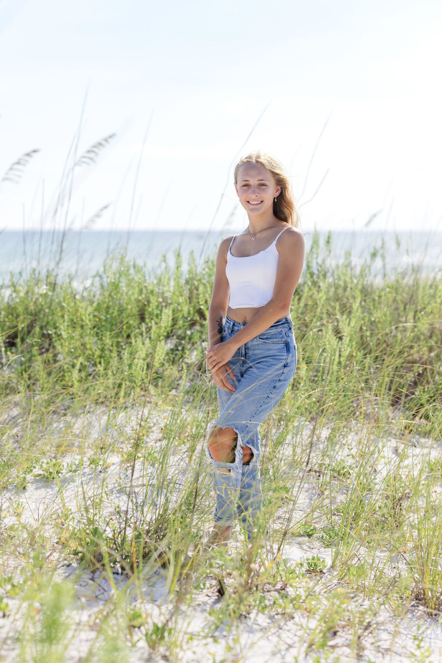 Summer beach photo session in the sand dunes with sea grass and soft natural lighting.