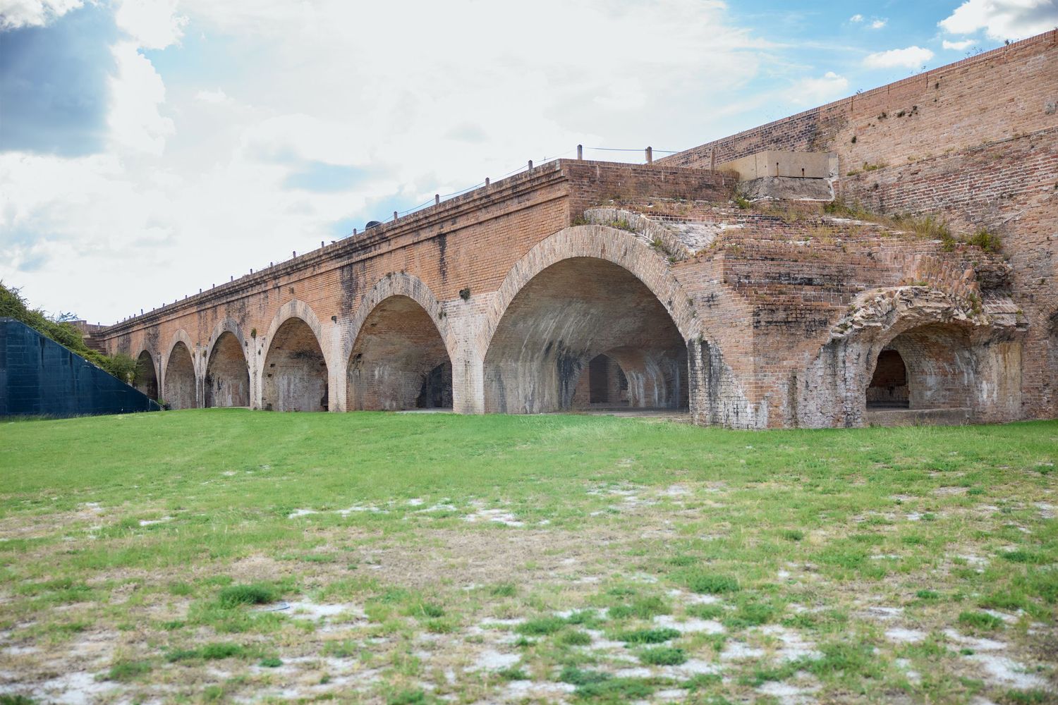 Ancient stone arches and vaults of a historic military fortification stand against a barren hillside landscape.