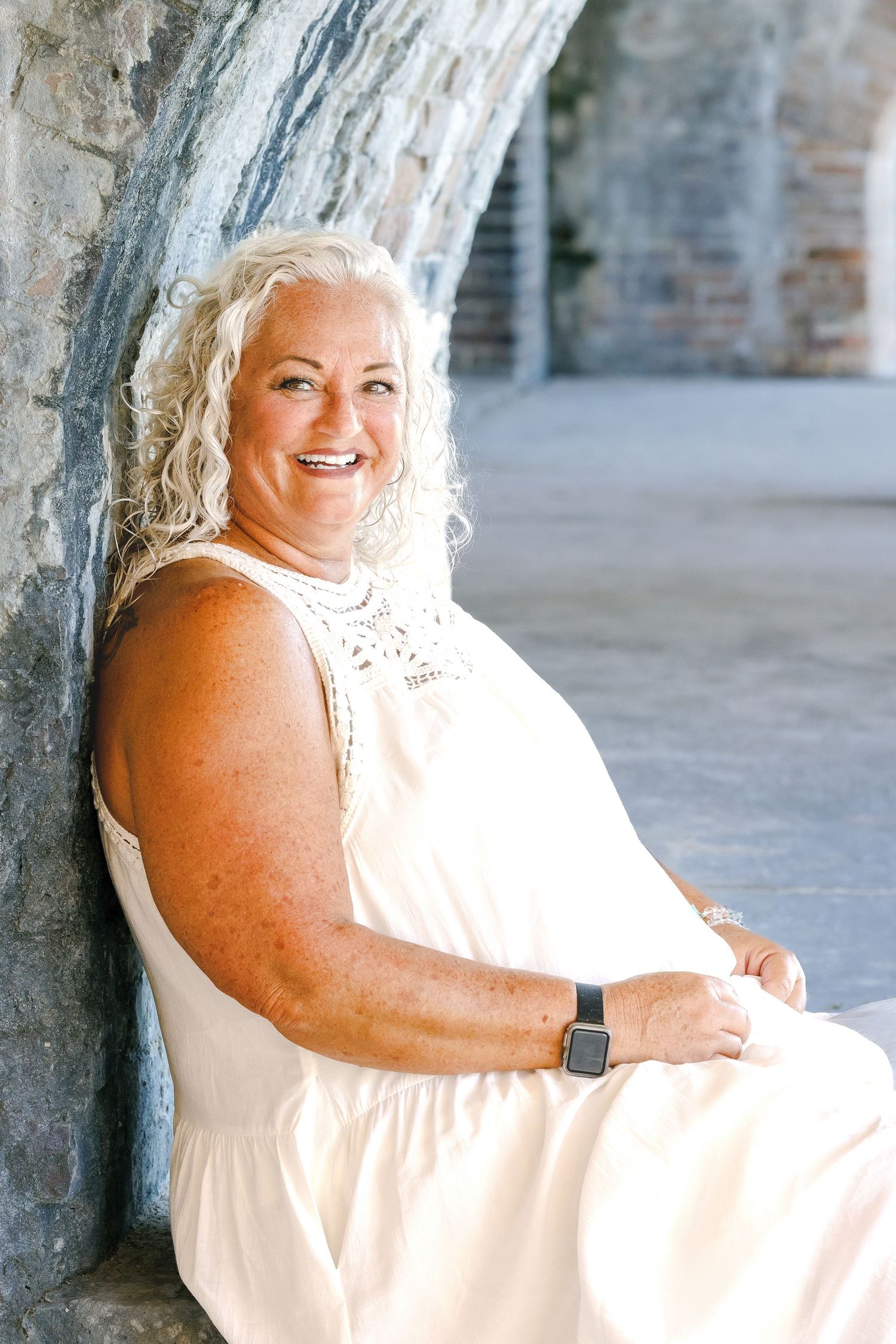 Person in a white dress poses against a stone wall in a series of candid outdoor portrait shots.