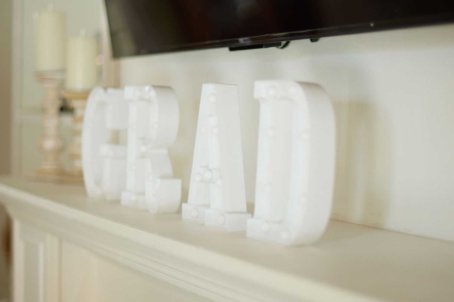 White decorative letters spelling GRAD displayed on white mantel.