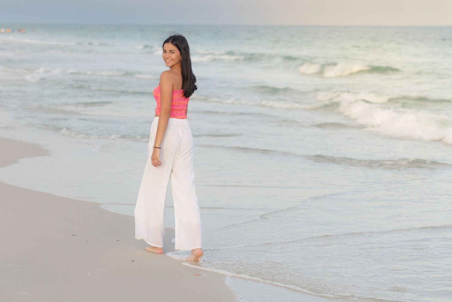 People strolling along tranquil beach shore during sunset.