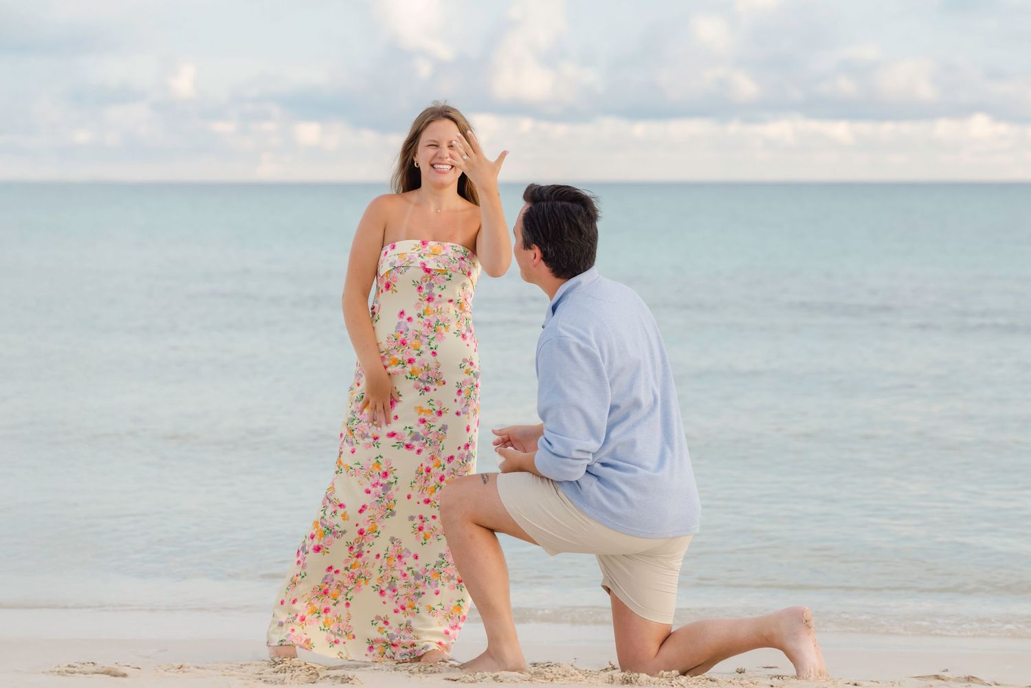 Two people share an intimate moment against a scenic beachfront backdrop during sunset.