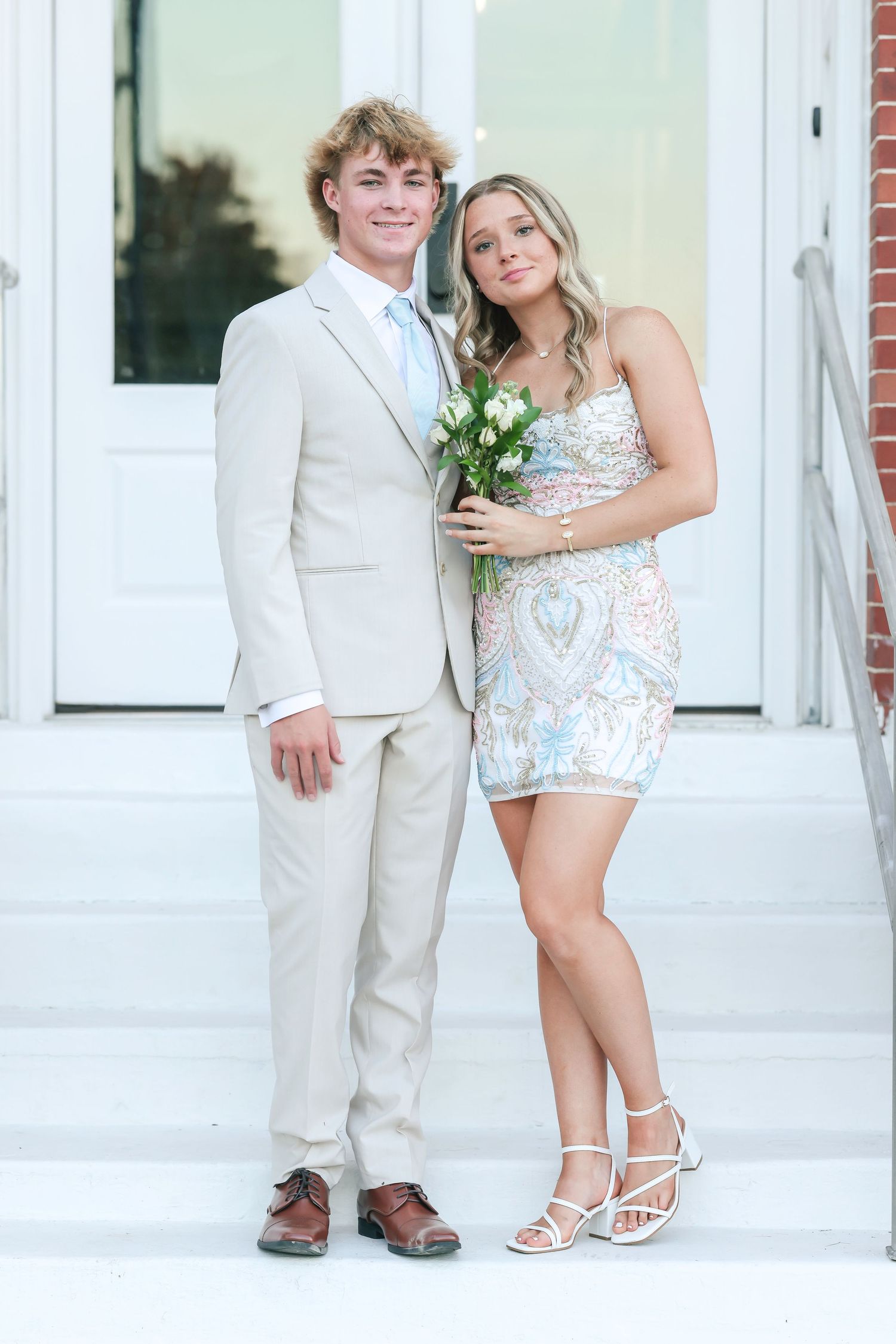 A loving couple poses in formal attire on their wedding day with white walls and doors in the background.