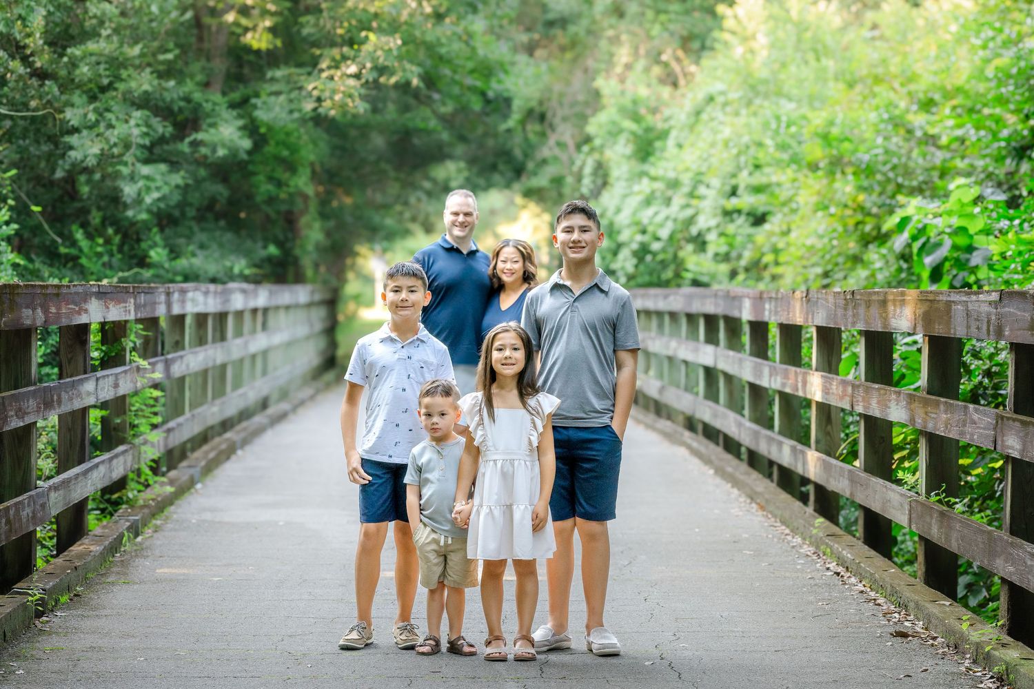 Group photo on a wooden boardwalk surrounded by lush green trees and foliage.