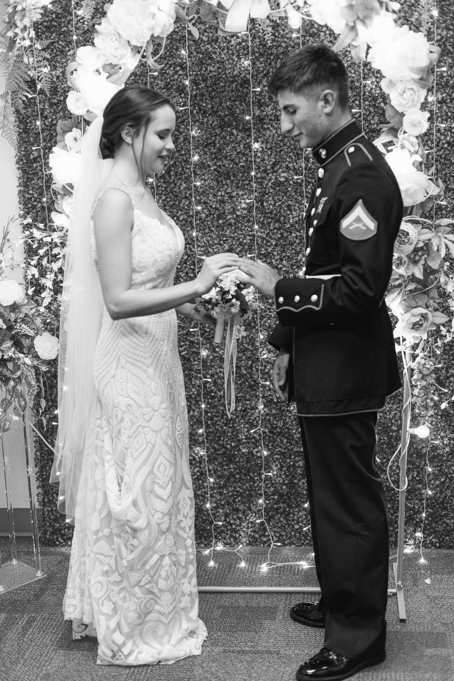 Black and white photo of a bride and Marine groom exchanging rings at their wedding ceremony.
