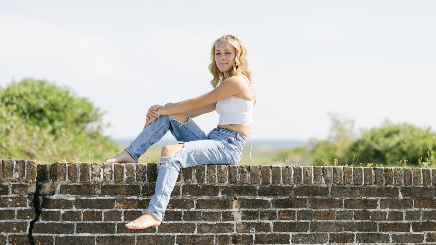 Five photos of a person in denim sitting on a brick wall show different poses and angles against a blurred background.