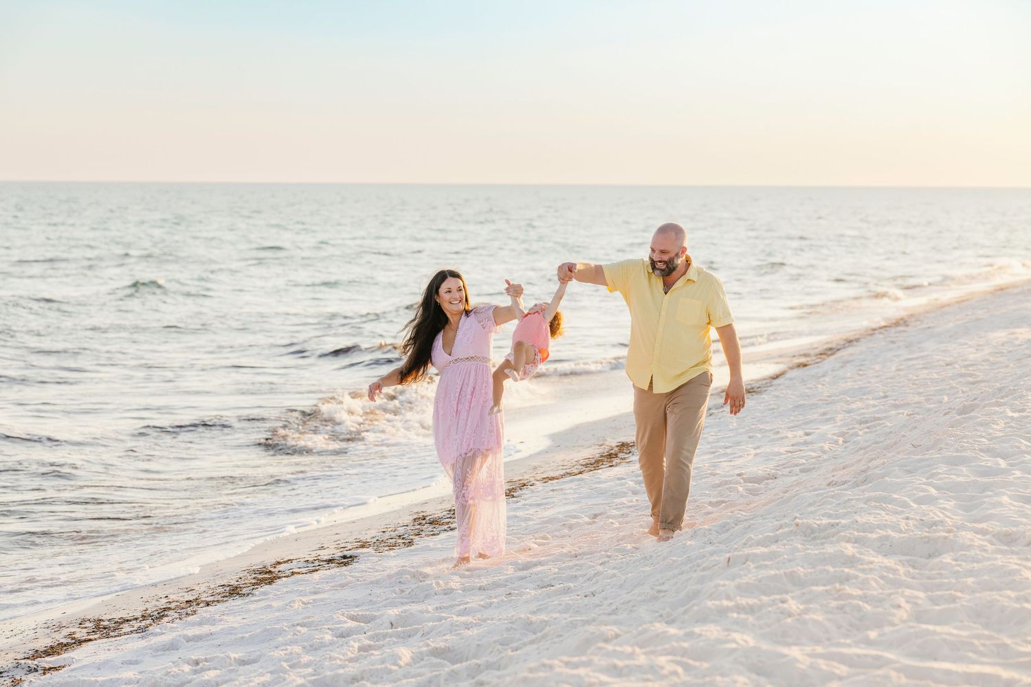 A group walks peacefully along a sun-drenched beach with rolling waves in the background.