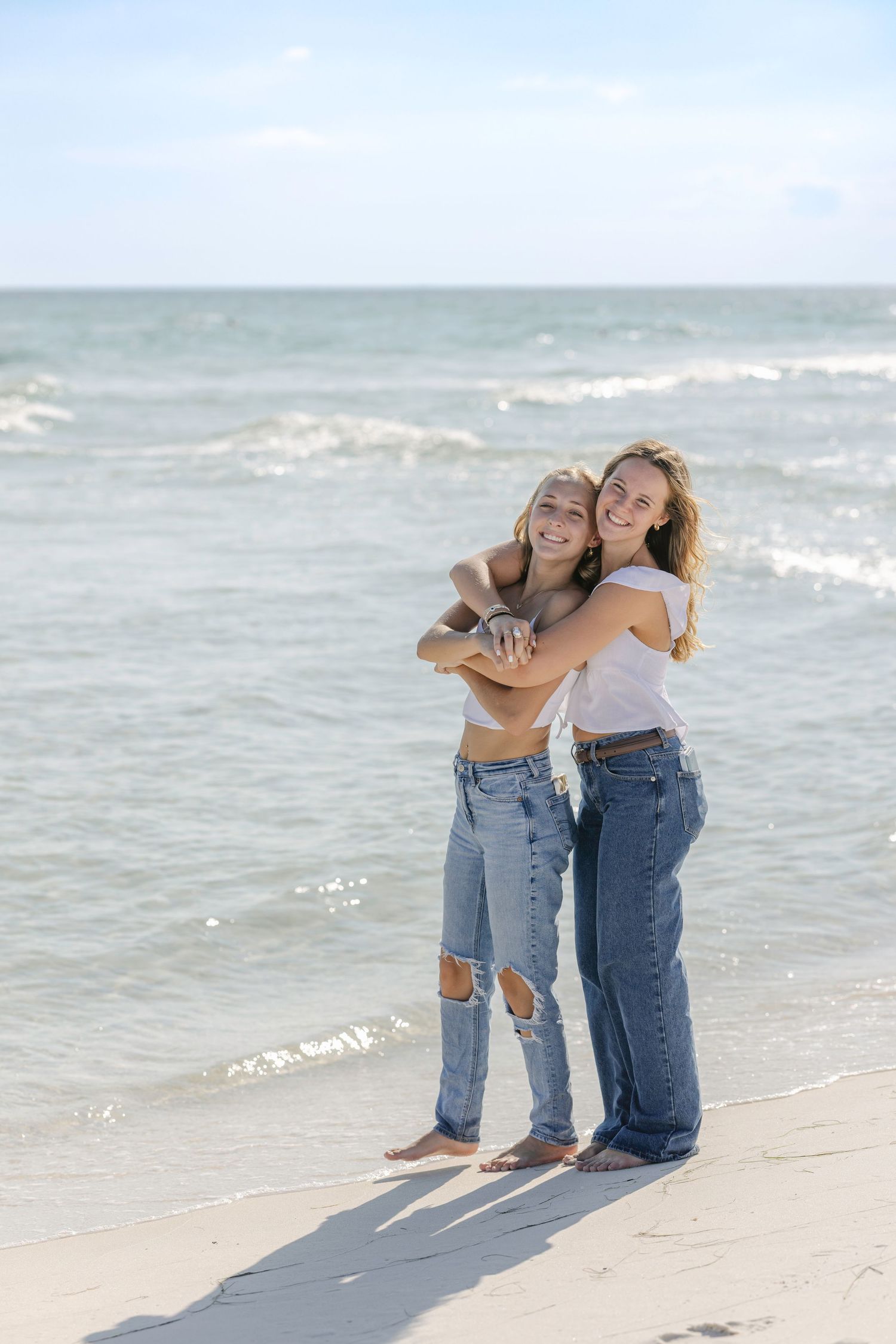 Three serene beach photos showing friends embracing on a sandy shoreline with gentle waves in the background.