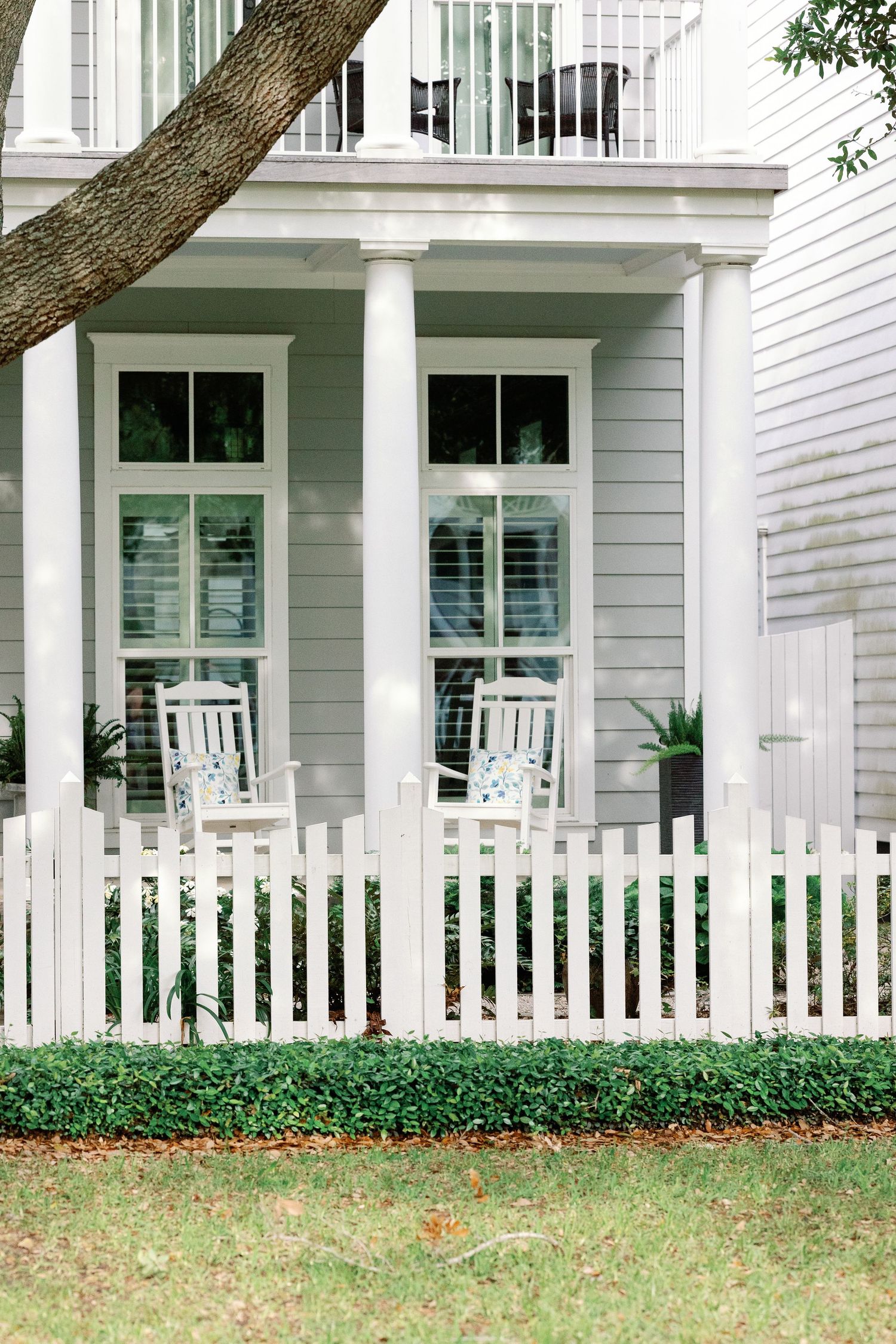Traditional white Southern-style house with white picket fence and large windows on front porch.