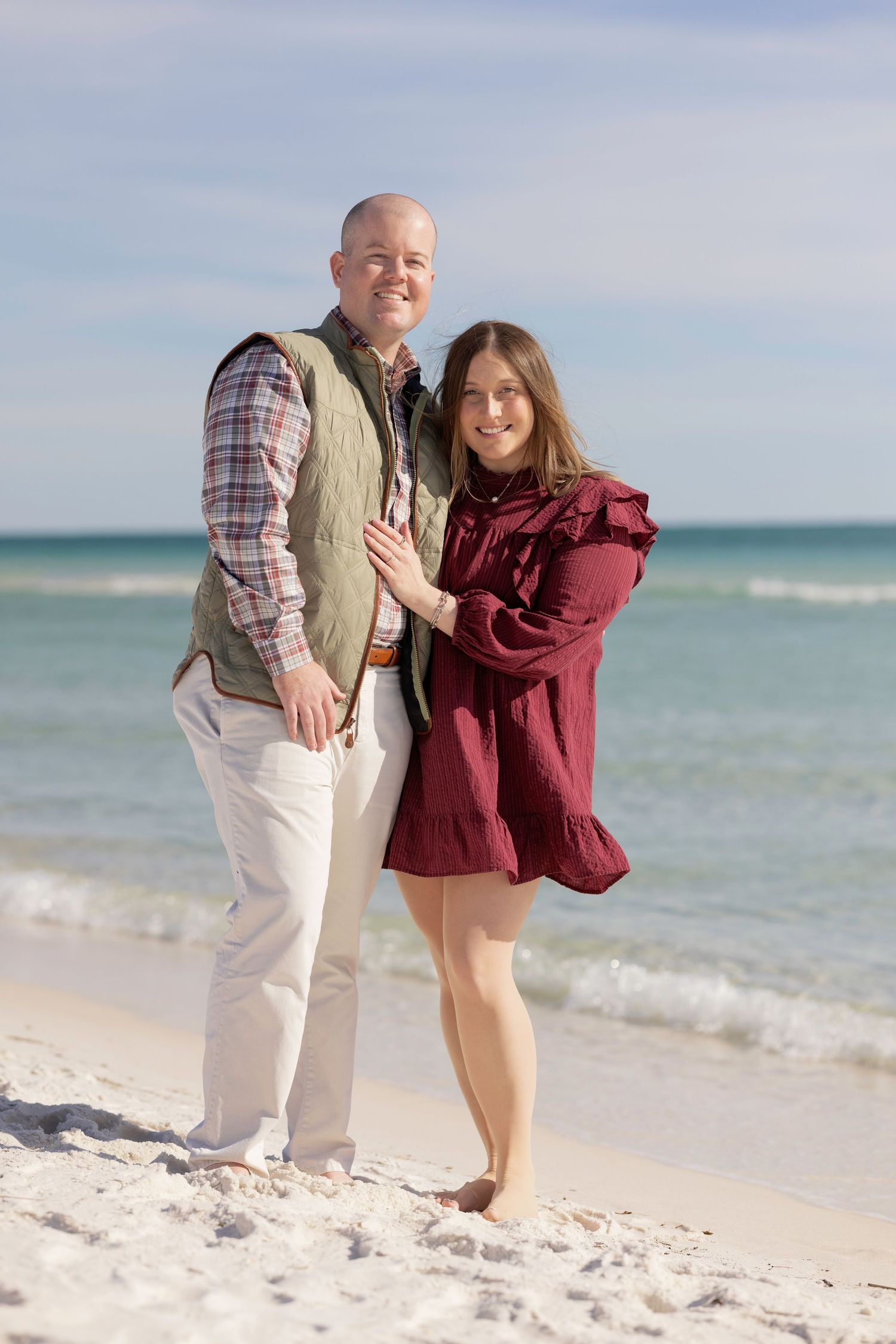 A couple shares a romantic moment on a pristine beach with turquoise ocean waters in the background.
