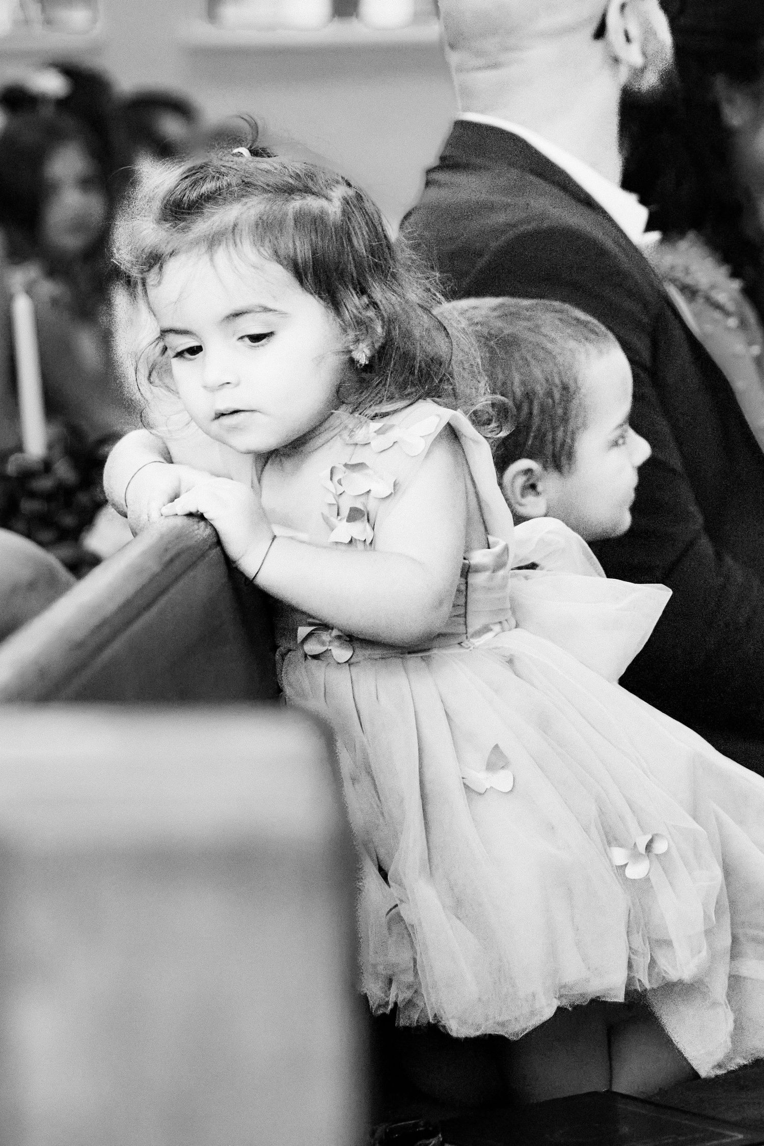A series of black and white photos showing a young child in a white dress in different poses.