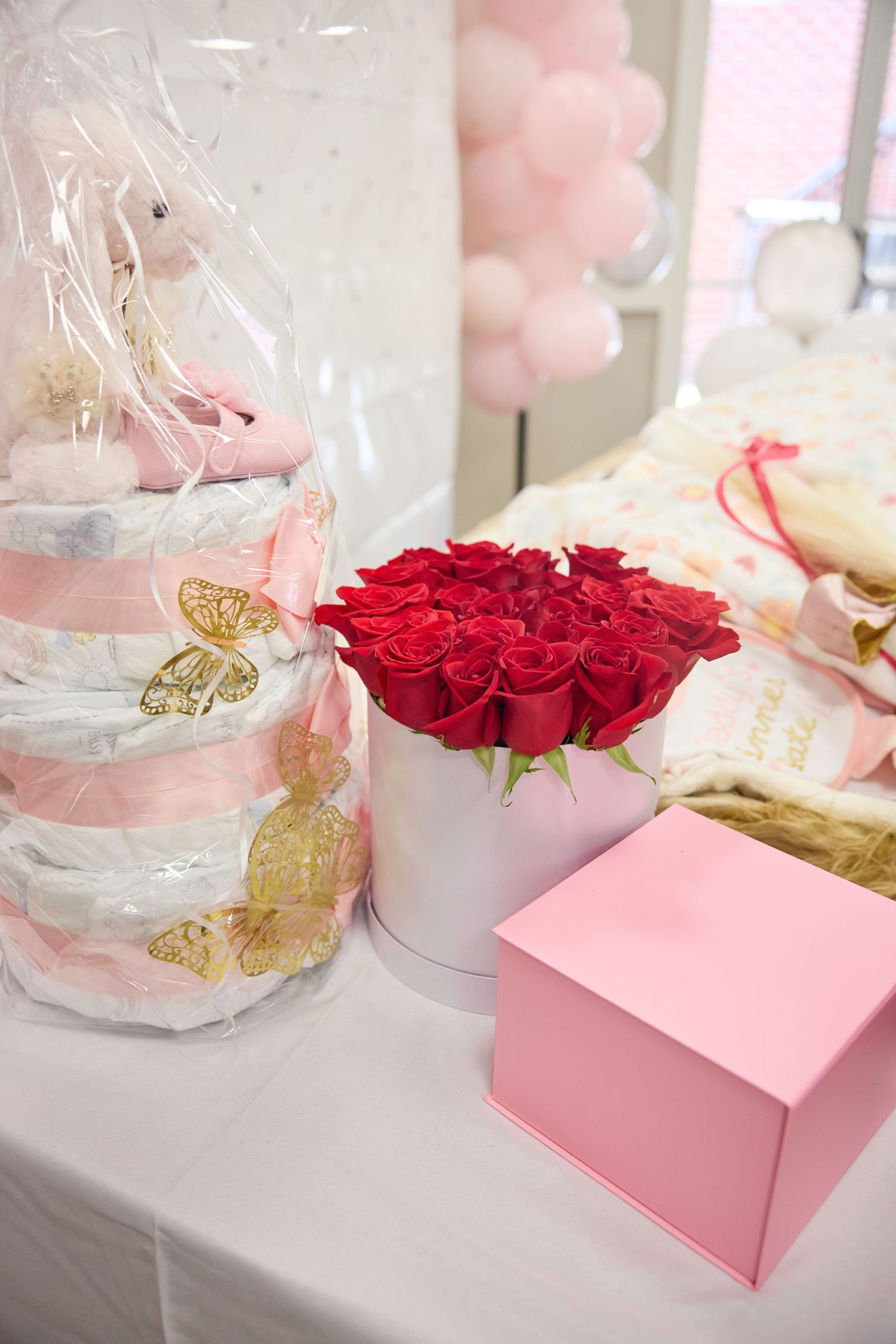 A romantic arrangement of red roses in a white box with pink accents and decorative gold butterflies on display.