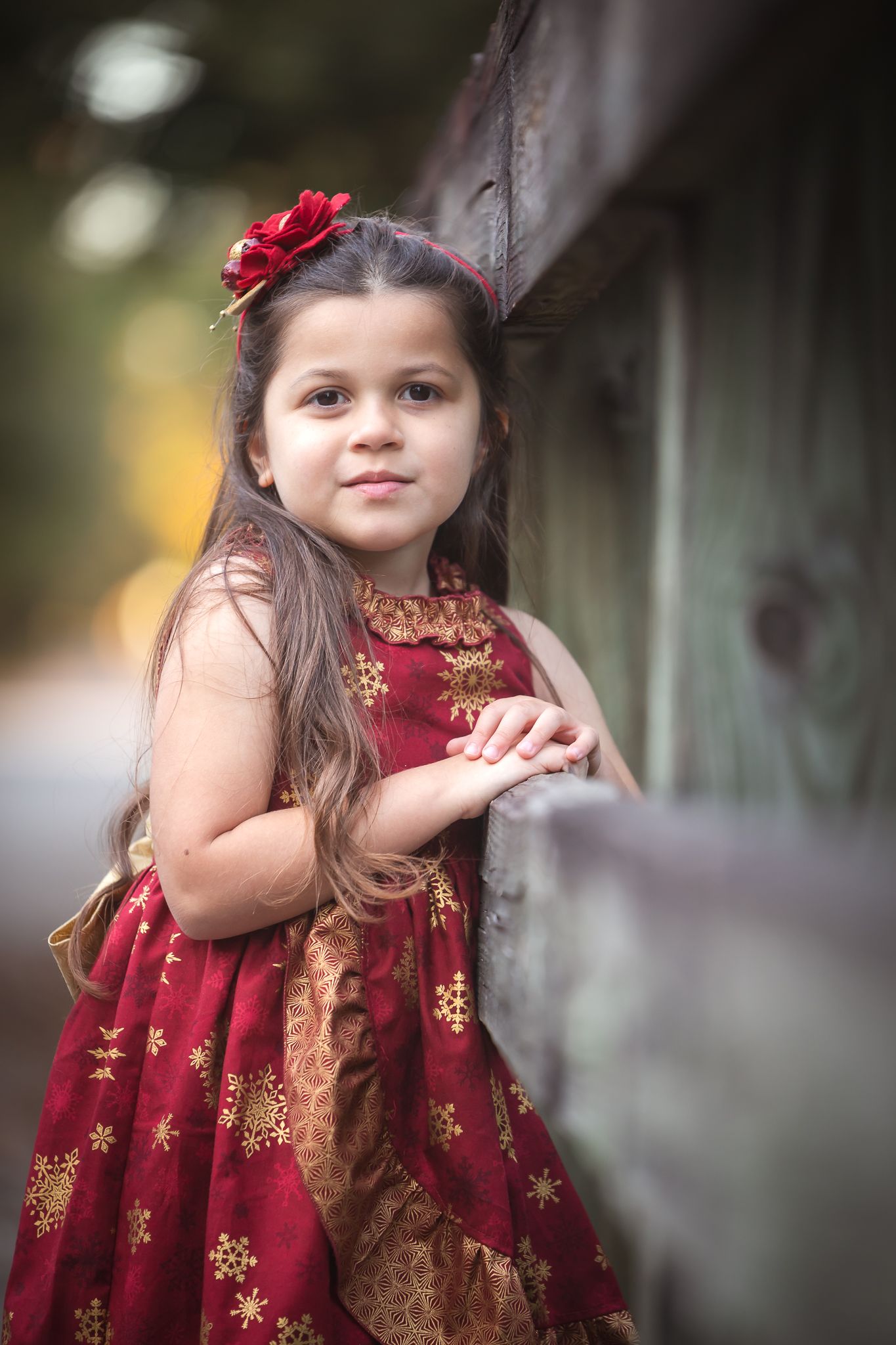 Child in festive red and gold dress with floral detail poses outdoors in a series of candid shots.