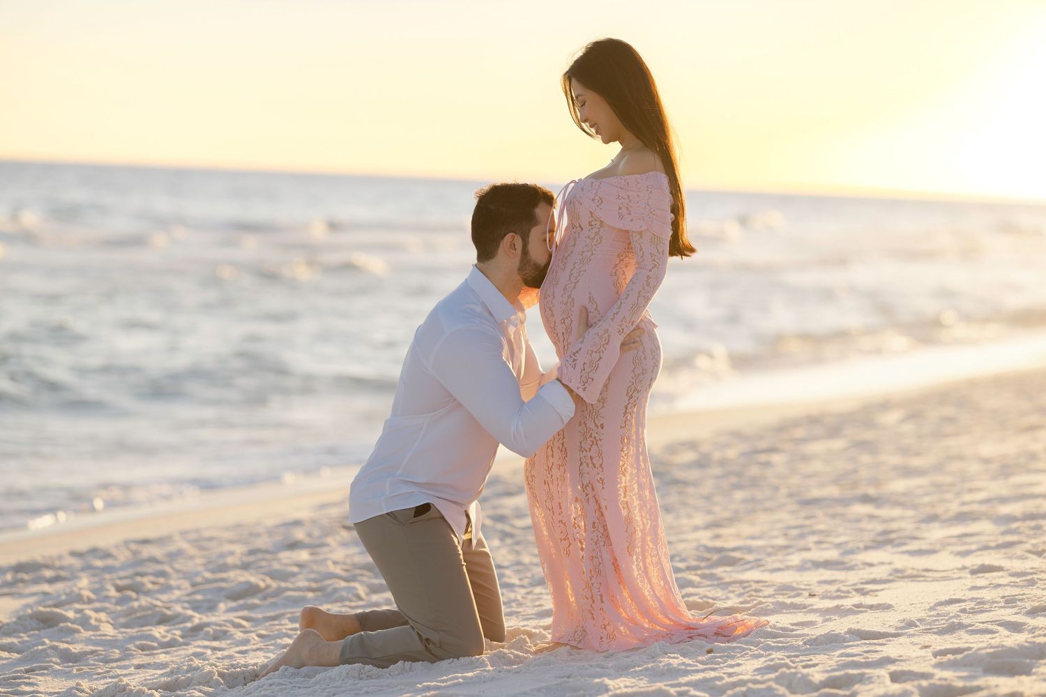 A couple sits together on a sandy beach at sunset creating a romantic seaside moment.