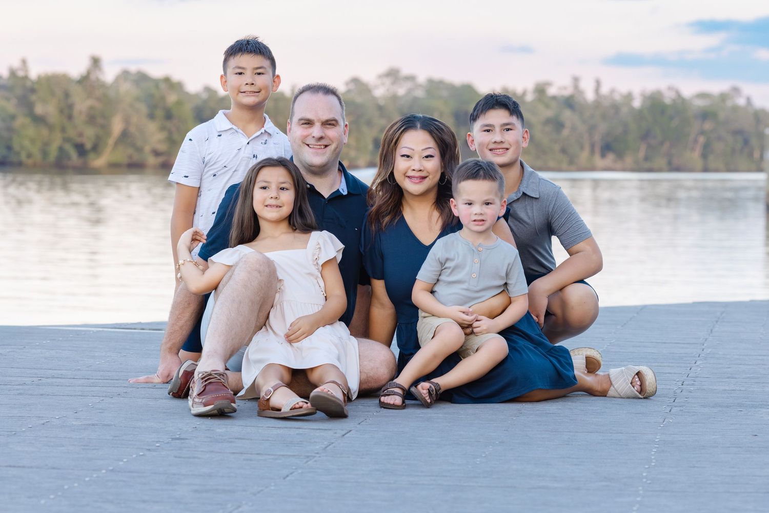 Family portrait taken outdoors at a scenic lakeside location during sunset.
