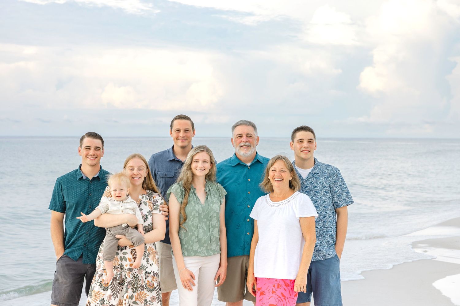 Family gathering at the beach with waves crashing and cloudy sky in the background.