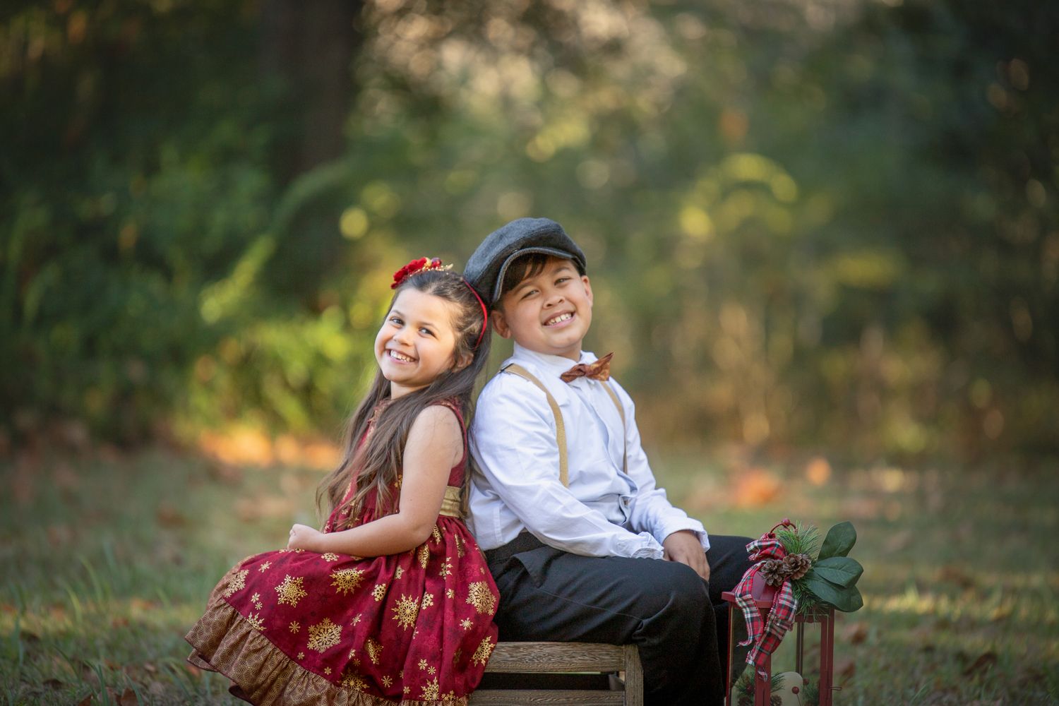 Two children share a laugh while sitting together on wooden steps in an outdoor autumn setting.