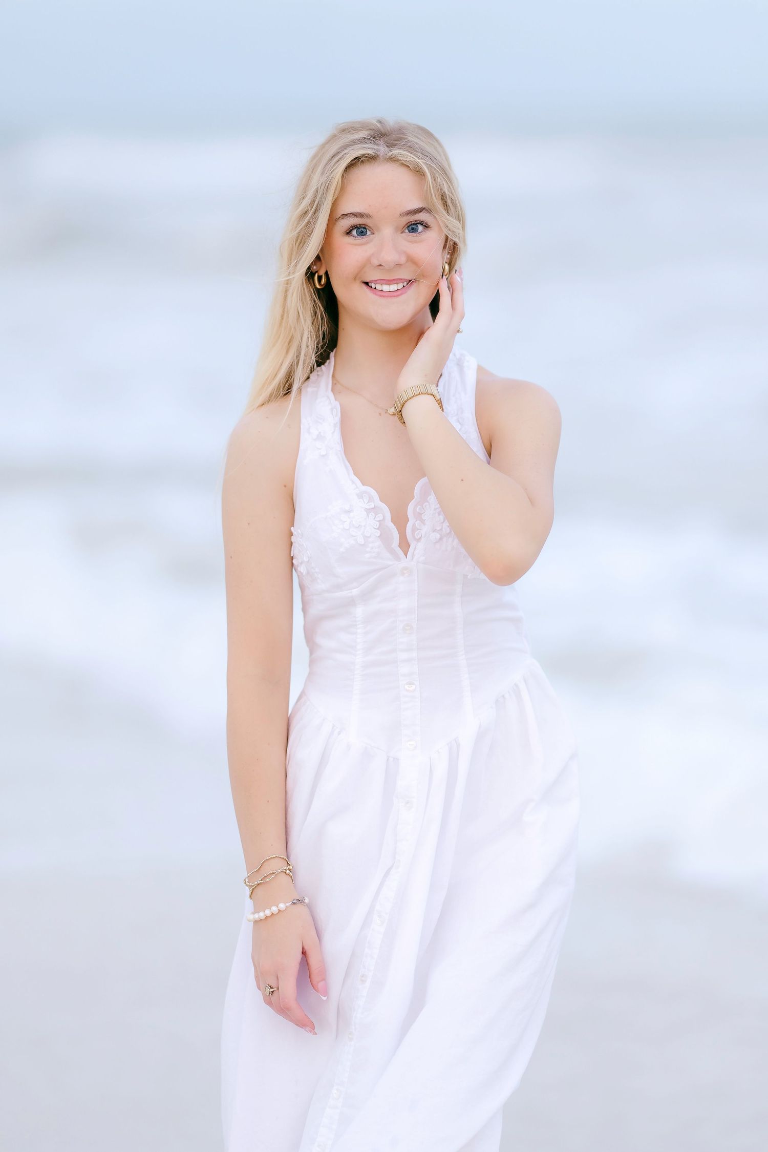 Light and airy beach photoshoot series with white dress against pastel sky background.