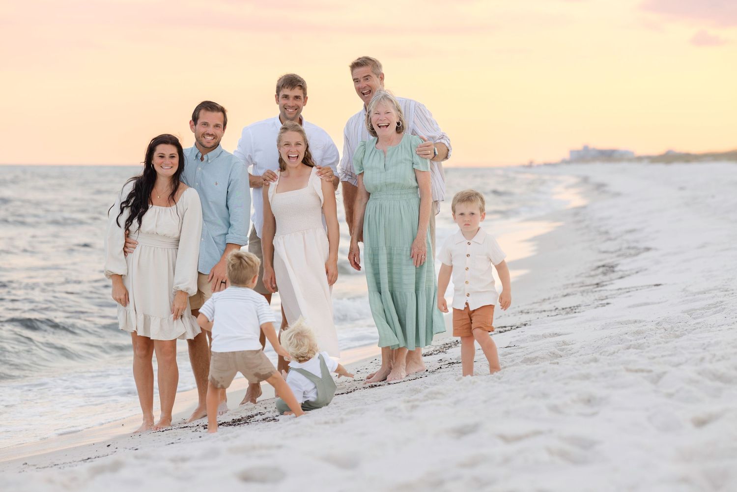 A group enjoys a serene sunset moment together while walking along a white sandy beach.