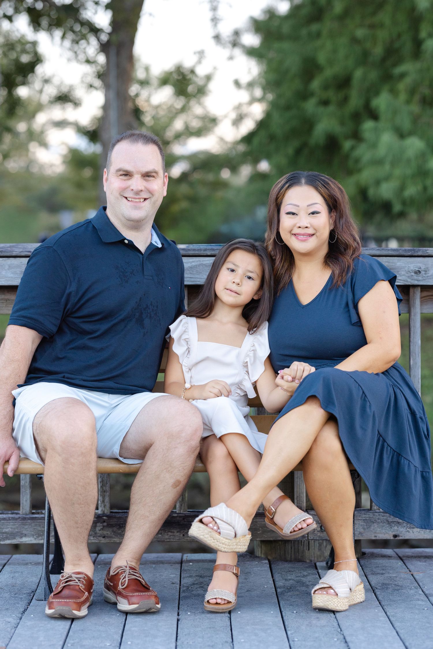 Family members sit casually together on a wooden bench wearing coordinated blue and white outfits.
