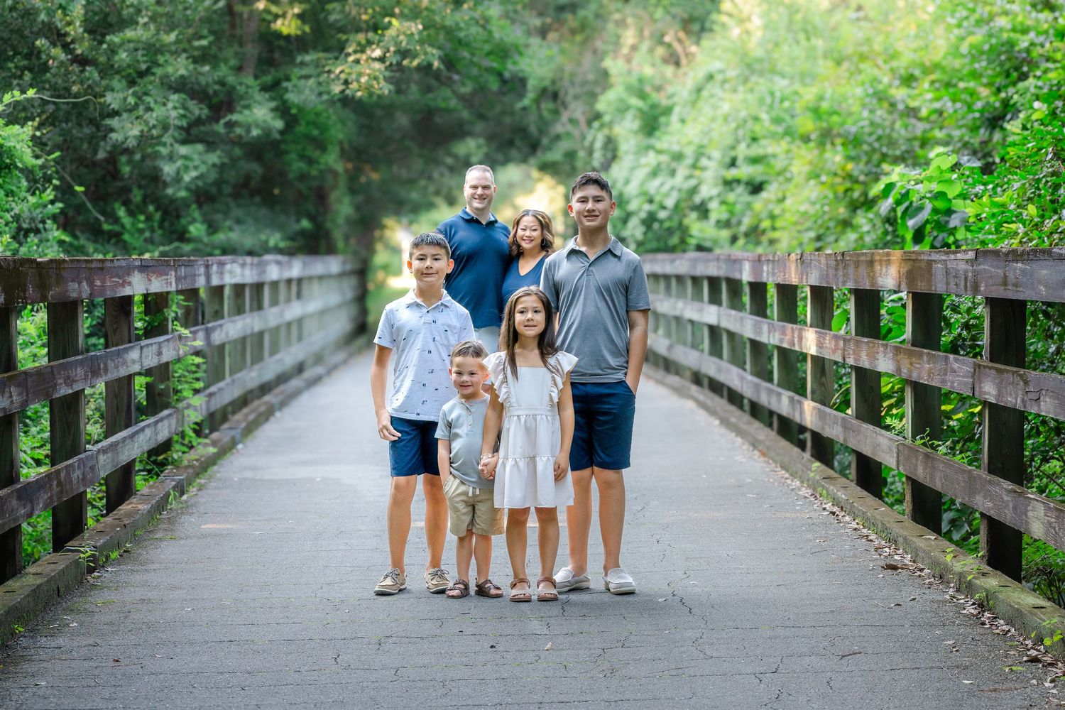 A group of people in coordinated blue and white outfits standing together on a wooden boardwalk in nature.