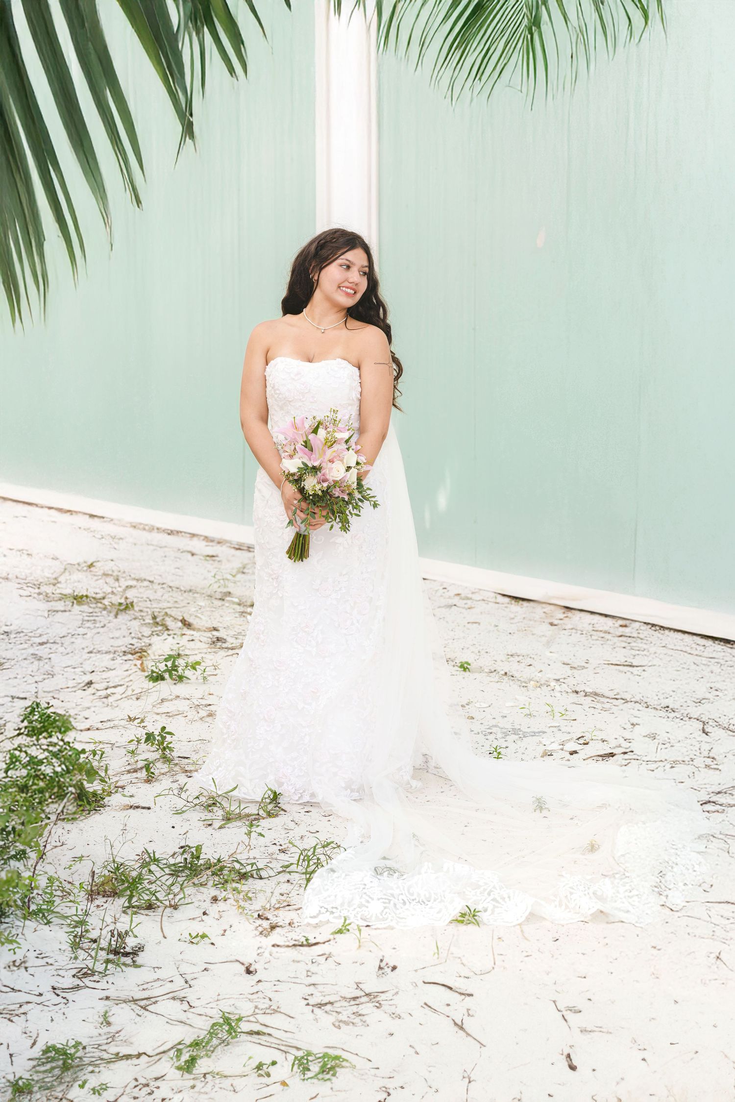 Bridal portrait session on beach with white dress and pink floral bouquet.