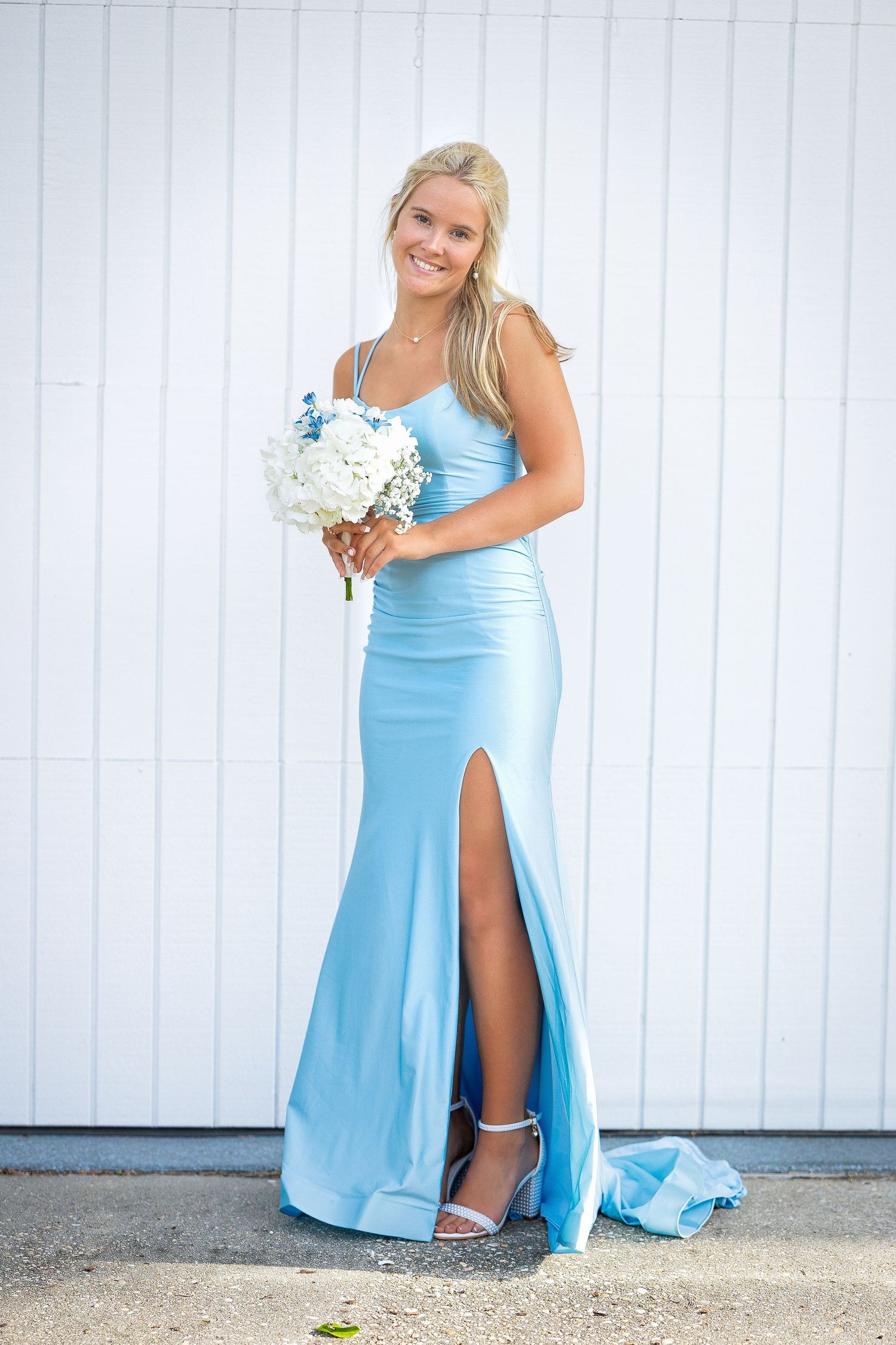 Woman in light blue formal gown poses against white wall in series of elegant photos.