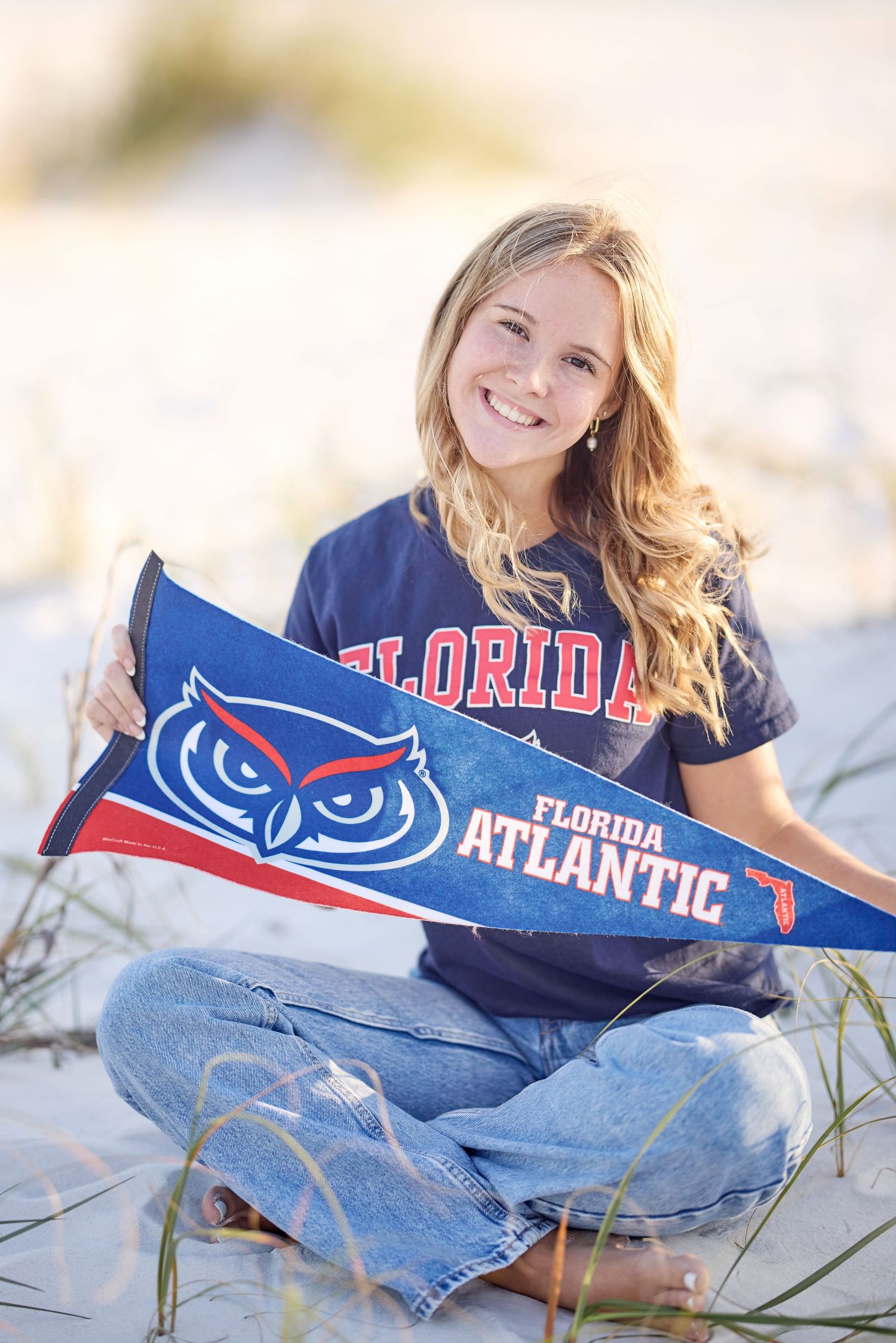 Florida Atlantic University spirit wear and merchandise displayed on beach sand with sea grass.