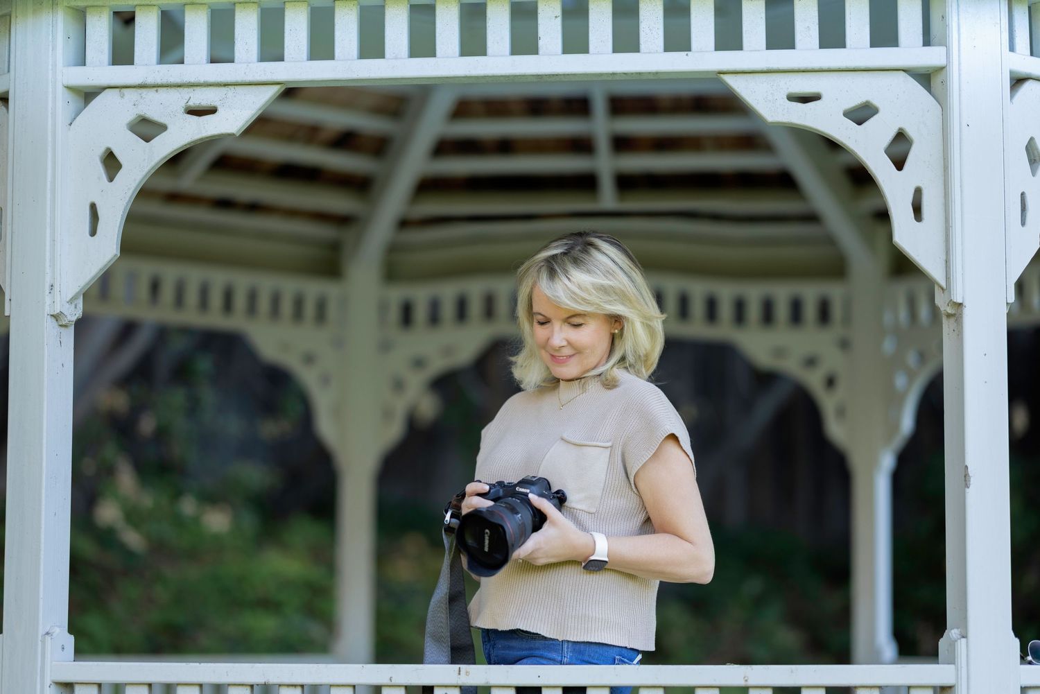 A photographer takes pictures under a white gazebo on a sunny day.