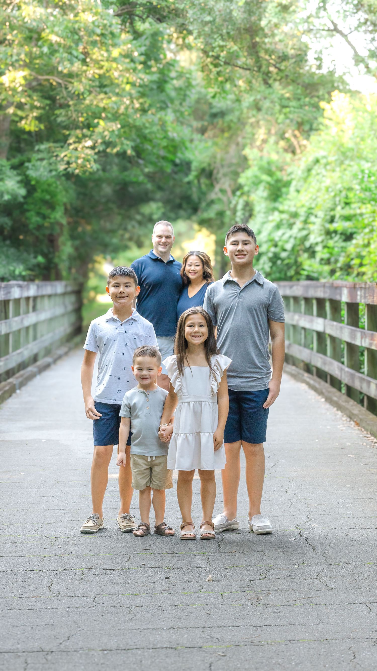 A group enjoying a sunny day together while standing on a wooden boardwalk surrounded by lush greenery.