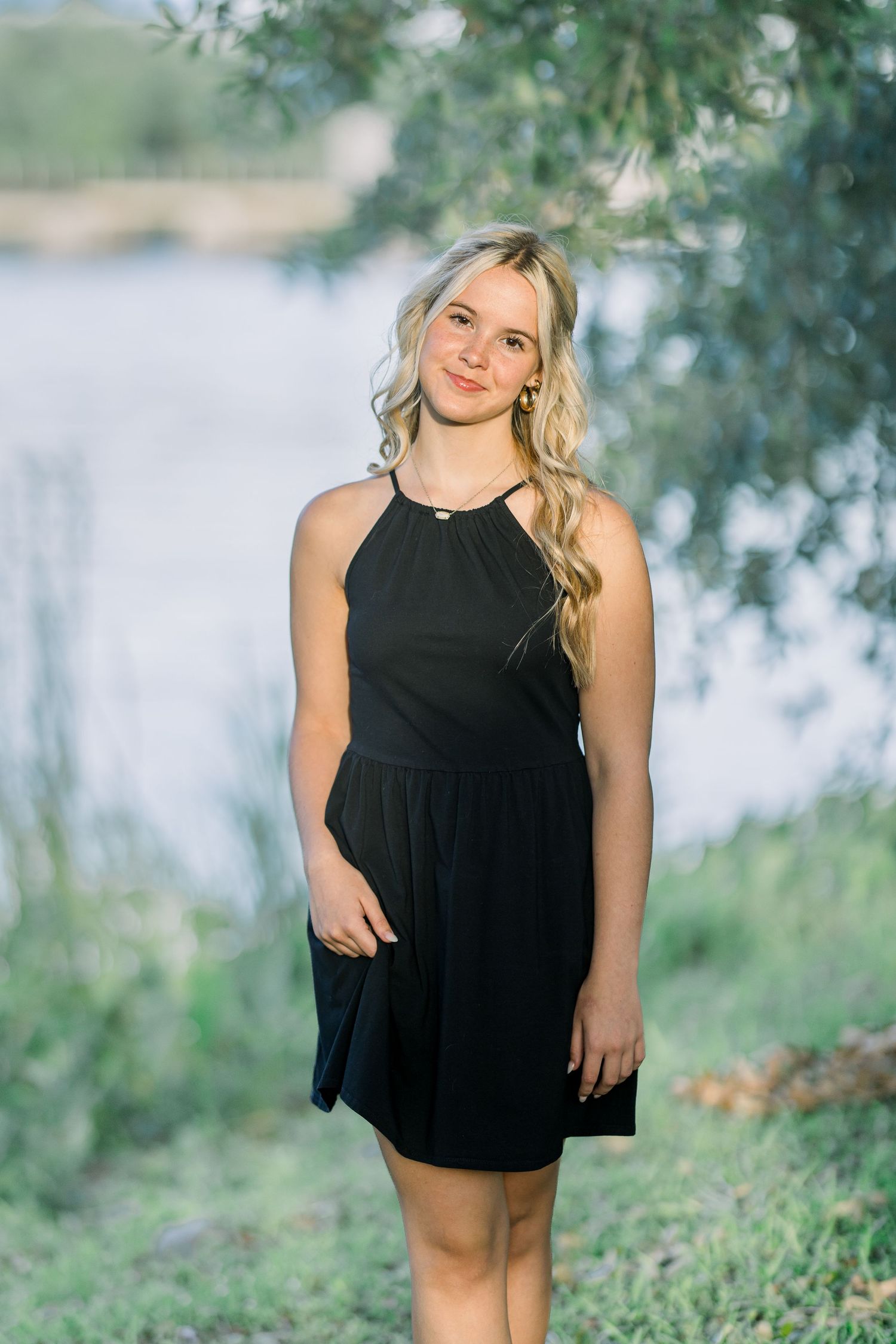 Outdoor portrait session near a lake with trees and natural scenery in the background.