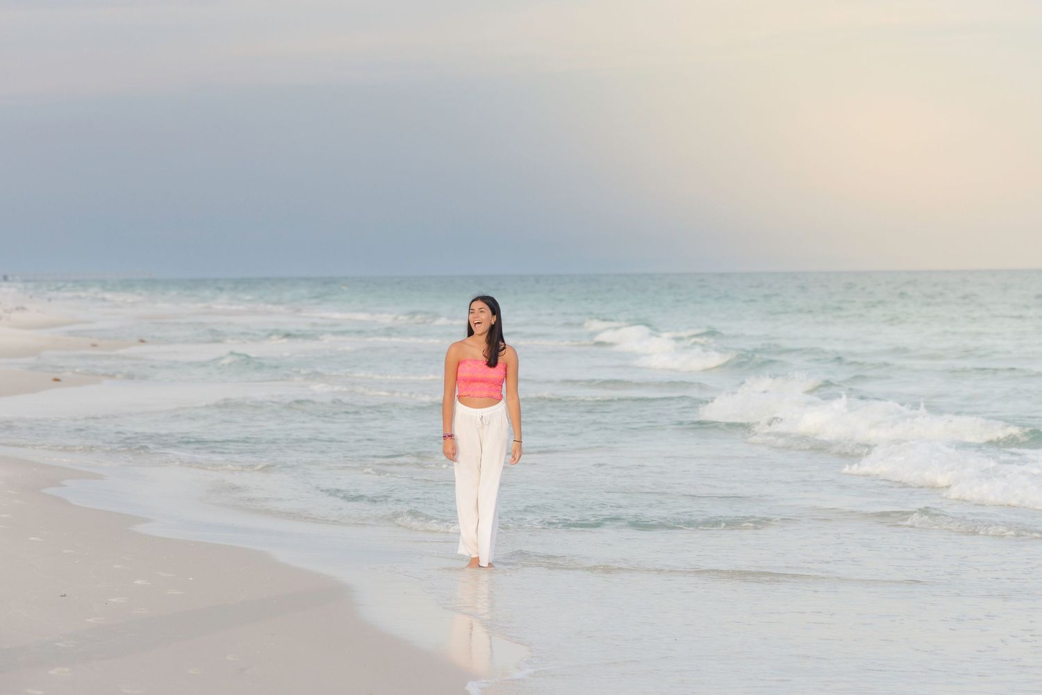 Ethereal beach portraits captured in soft lighting with white and coral beachwear.