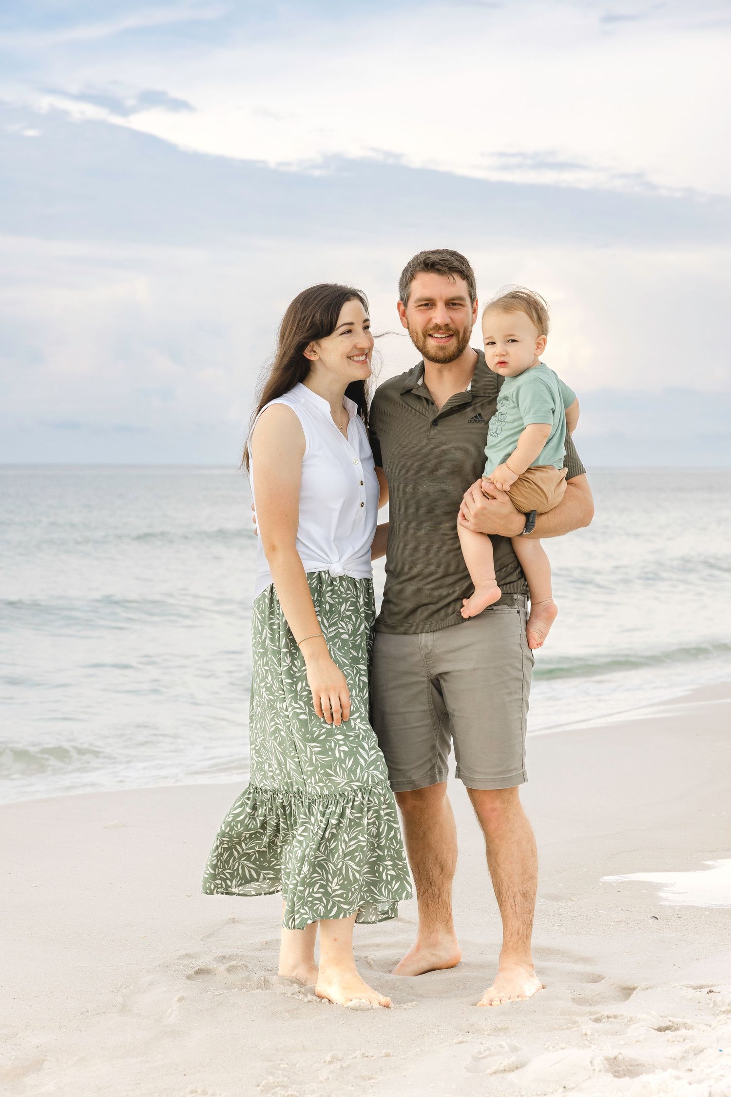 Family enjoying a tender moment together while walking along a serene beach at sunset.