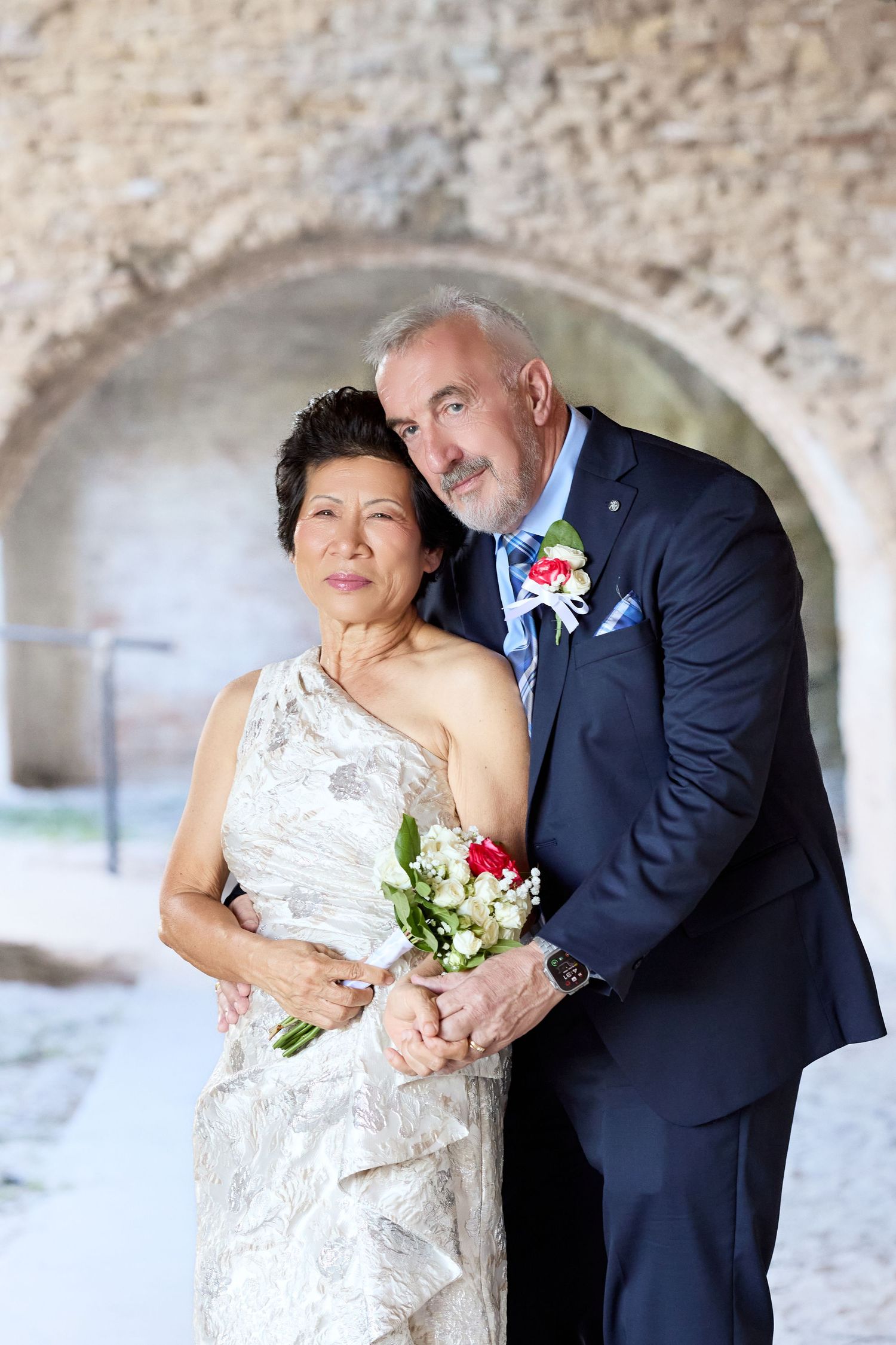 A romantic wedding couple shares intimate moments in a series of photos taken against a stone wall backdrop.