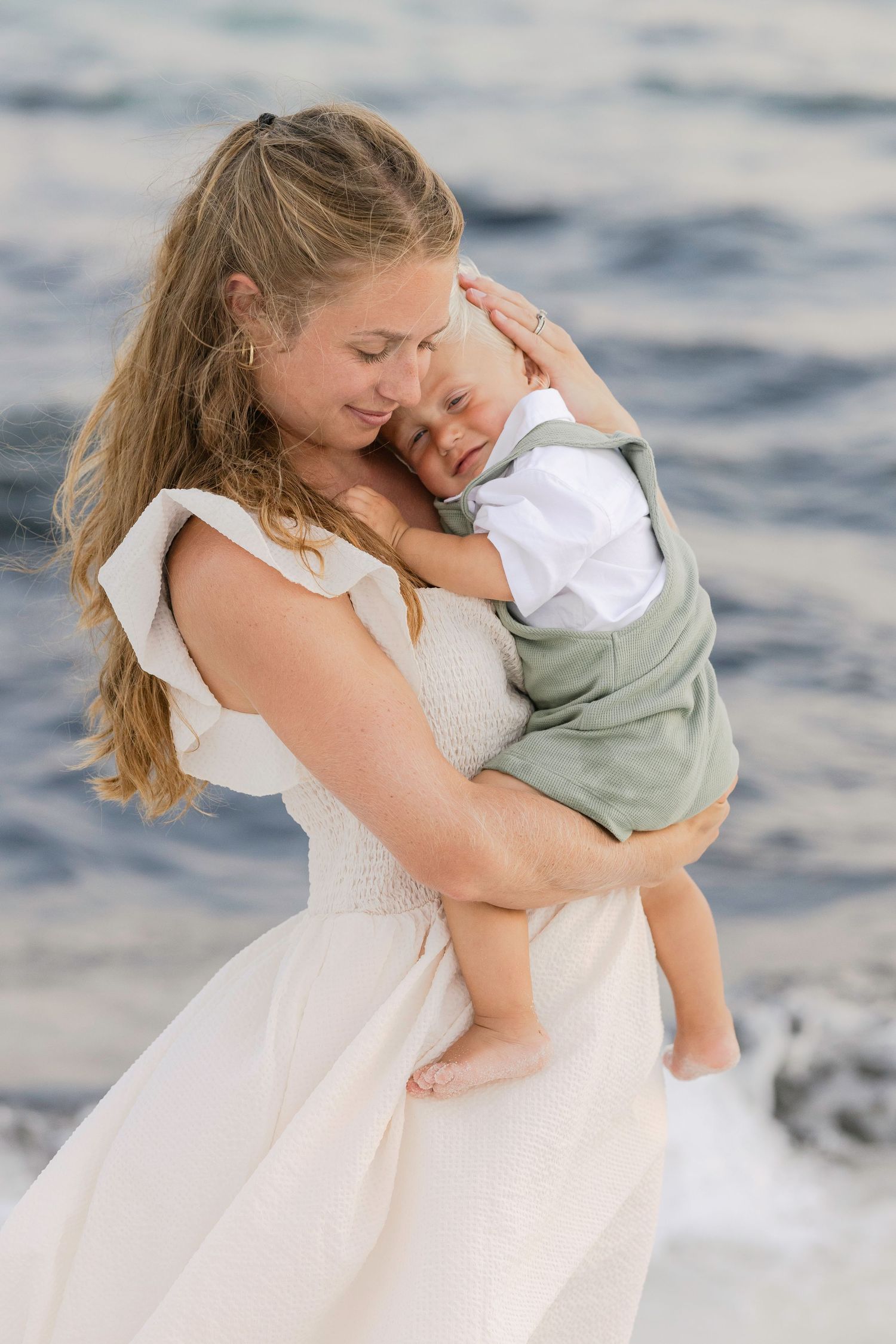 A tender embrace between mother and child is captured in a series of heartwarming moments by the ocean.