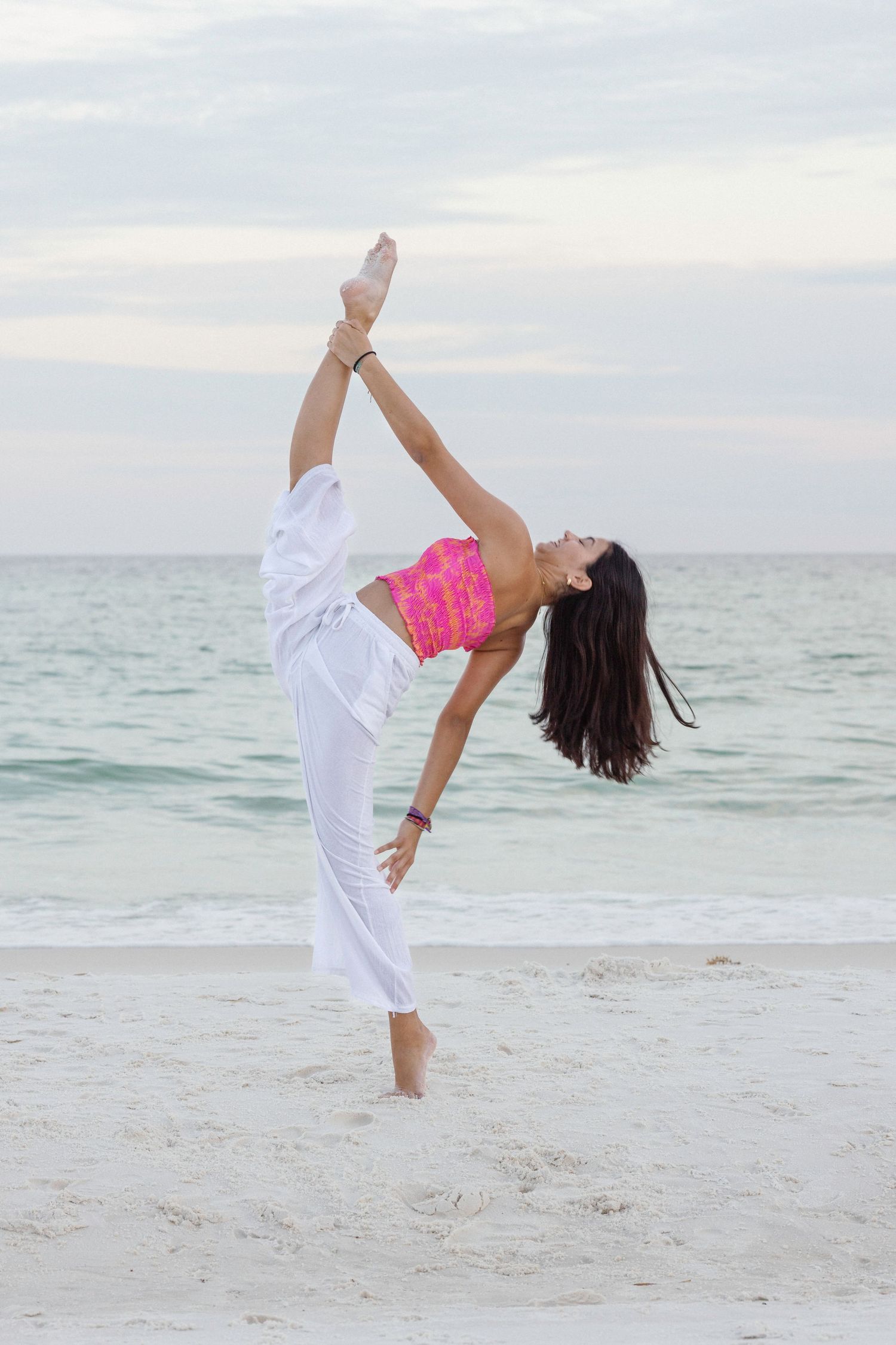 A sequence of dance poses performed on a white sandy beach with the ocean and cloudy sky in the background.